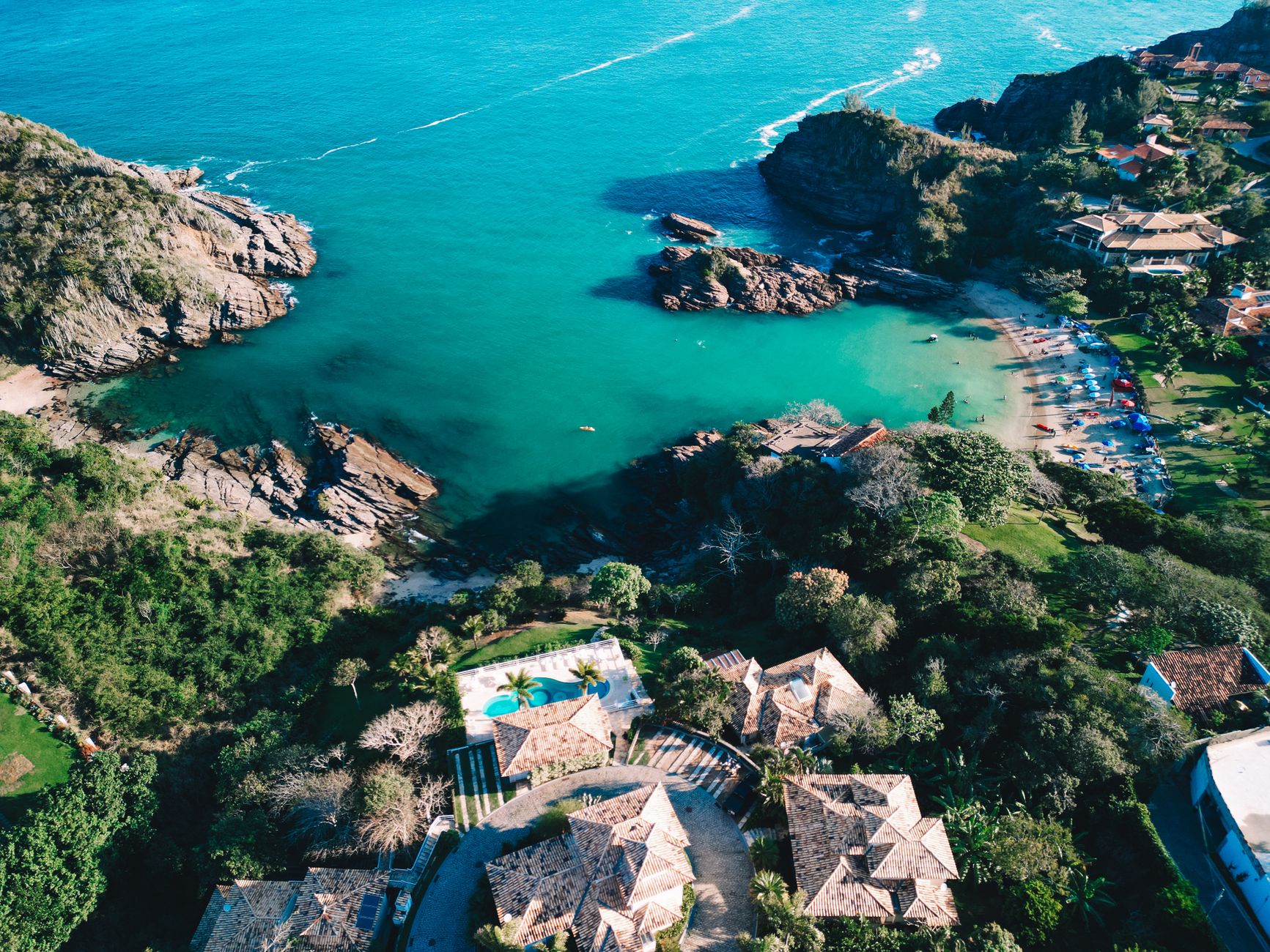 Stunning aerial view of Ferradurinha Beach in Búzios, Brazil showcasing turquoise waters and lush surroundings.