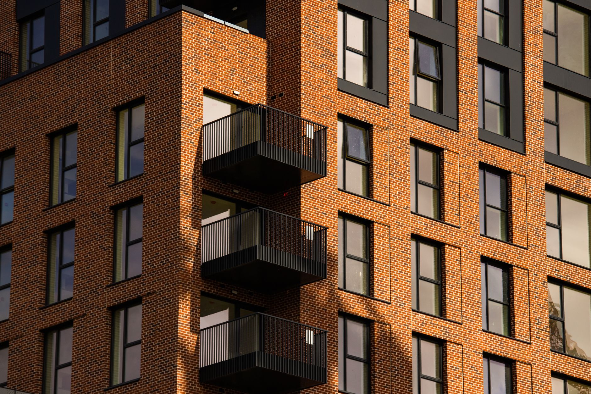 A striking view of a modern brick apartment facade with dark metal balconies in Dublin.