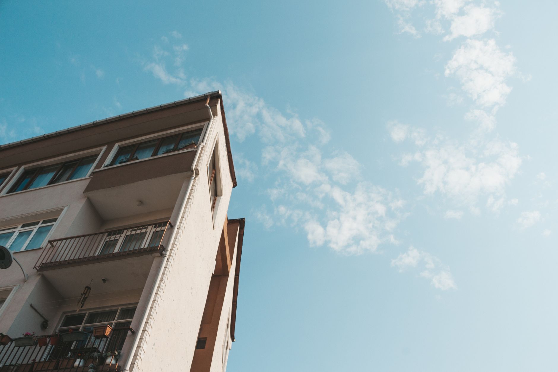 Low angle view of a modern apartment building with balconies against a clear blue sky.