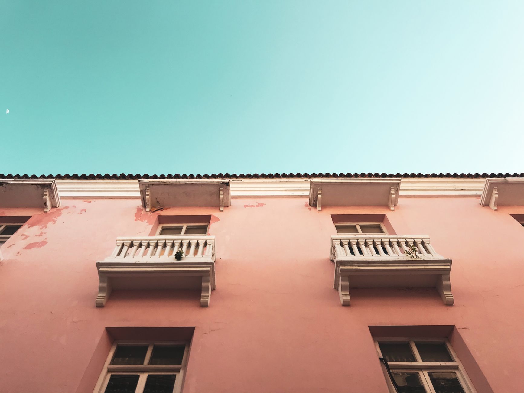 Pink colonial building with balconies in Cartagena against a blue sky.