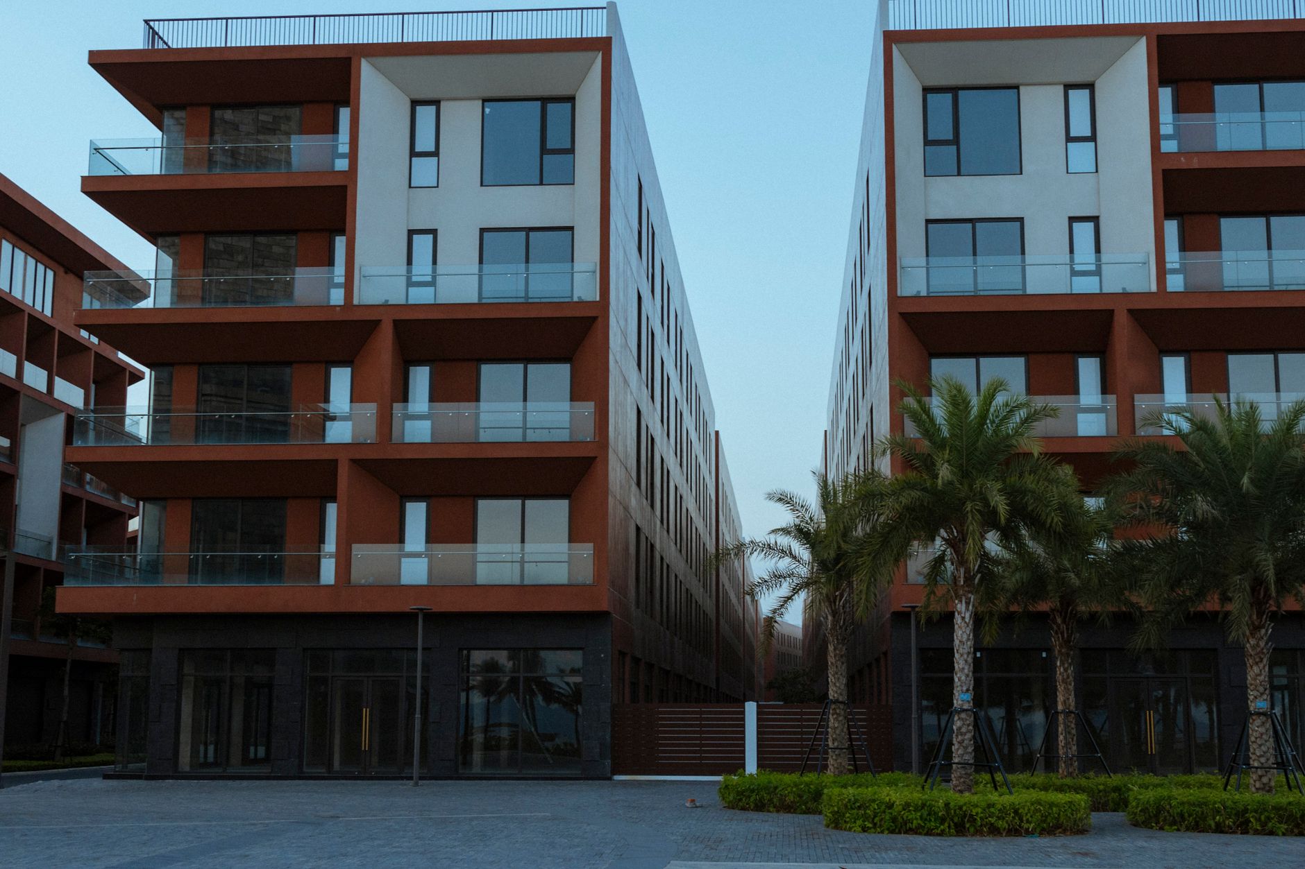Contemporary apartment buildings with balconies and palm trees in an urban setting.