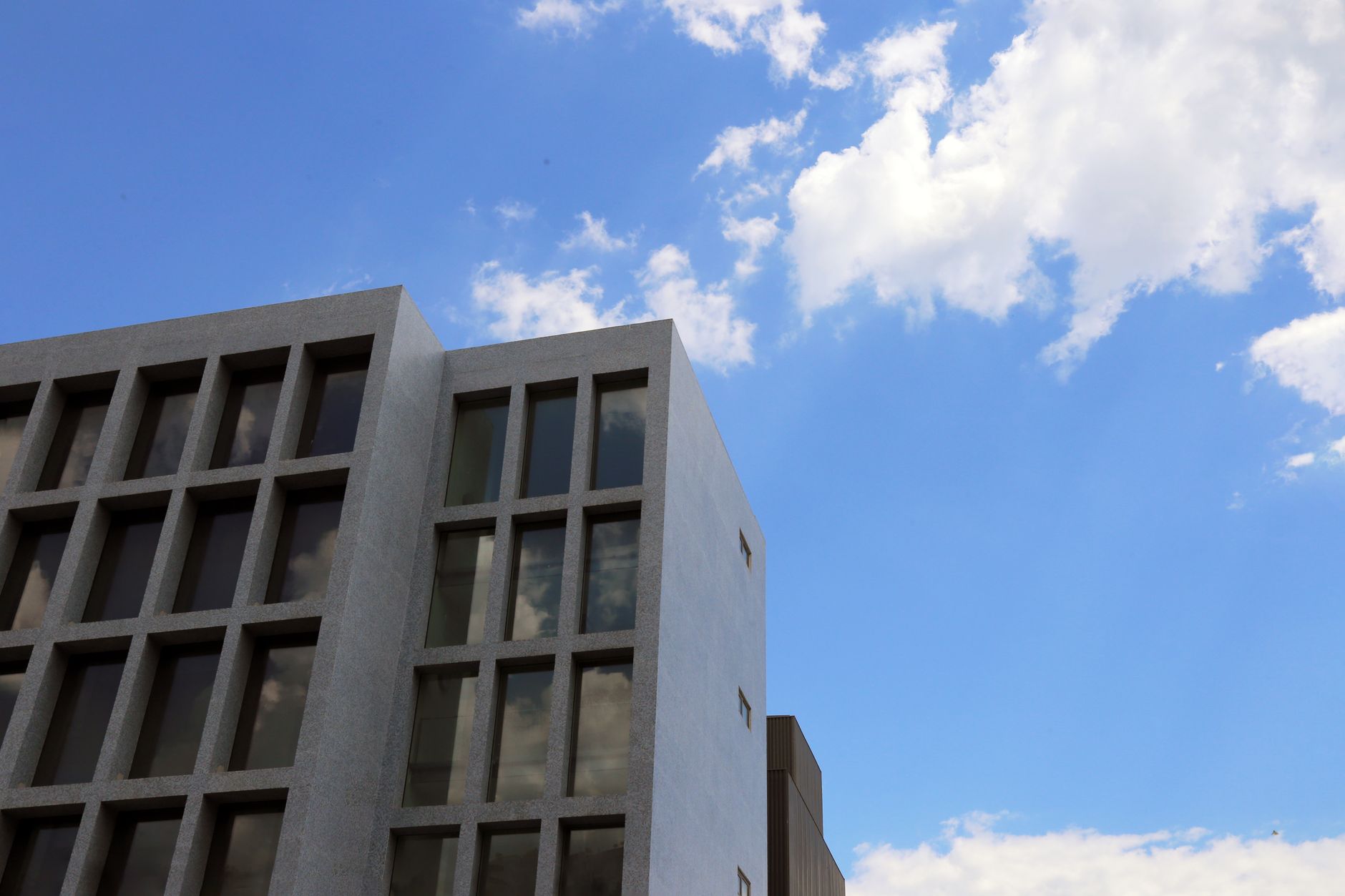 Low angle view of a modern building with a clear blue sky and clouds.
