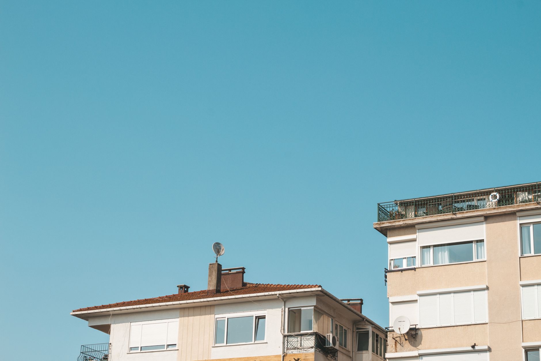 Low angle view of a contemporary building facade under a bright blue sky.