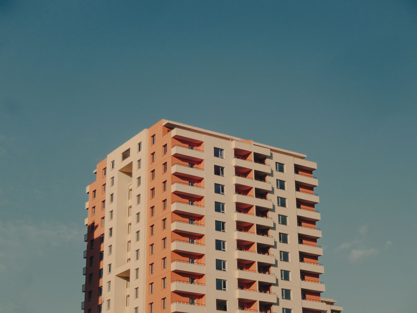 A modern high-rise building with a colorful facade against a clear blue sky.