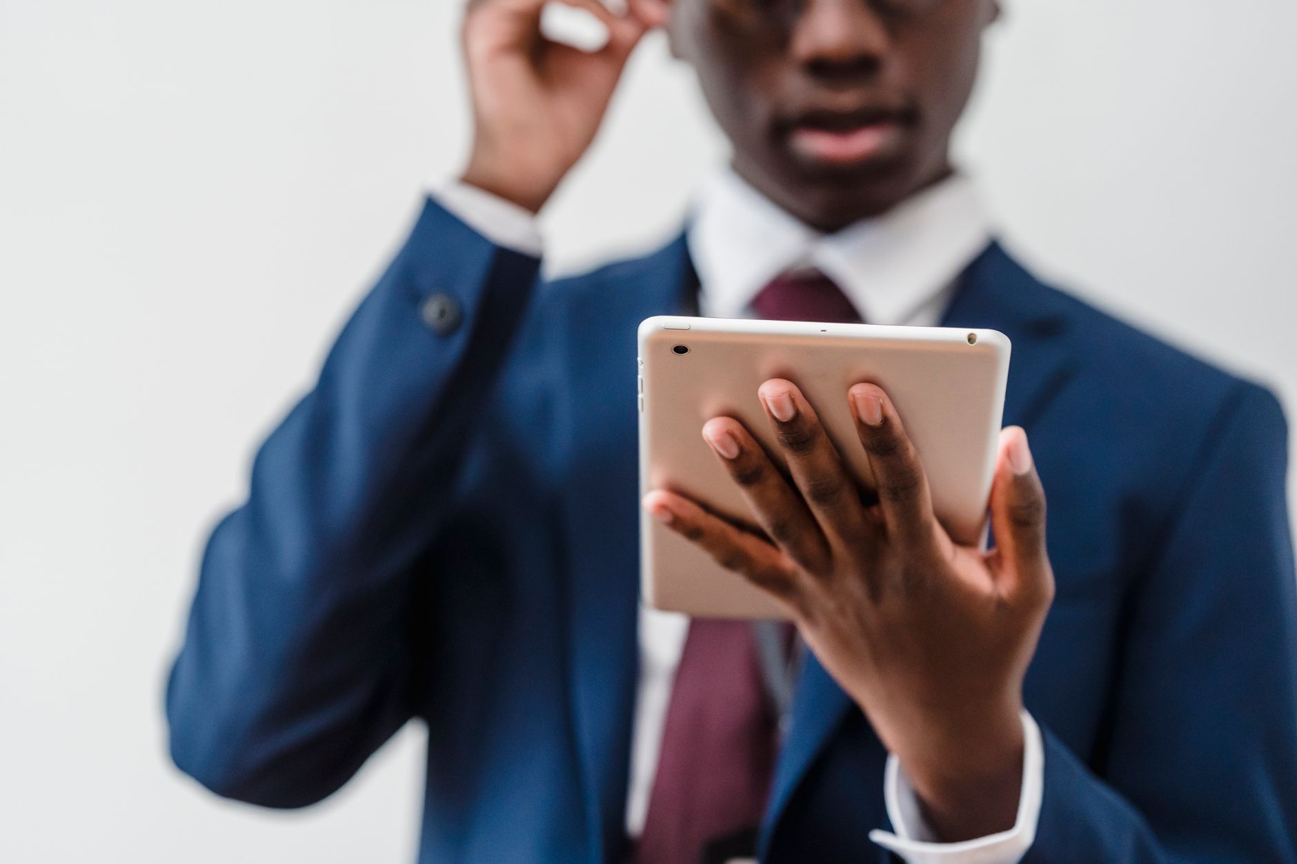Focused businessman in a suit interacting with a tablet indoors.
