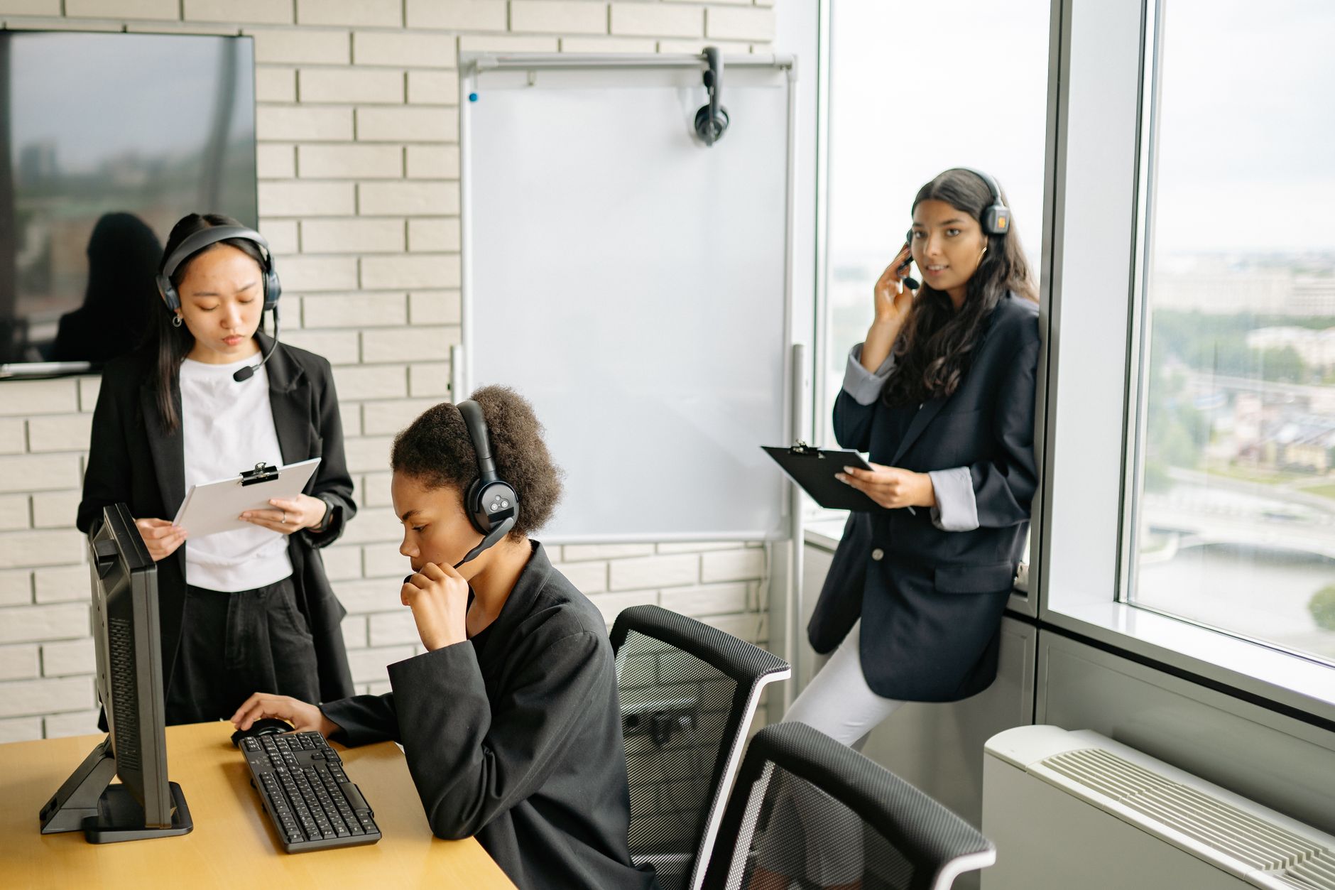 Professional women collaborating in a call center with headsets and computers.