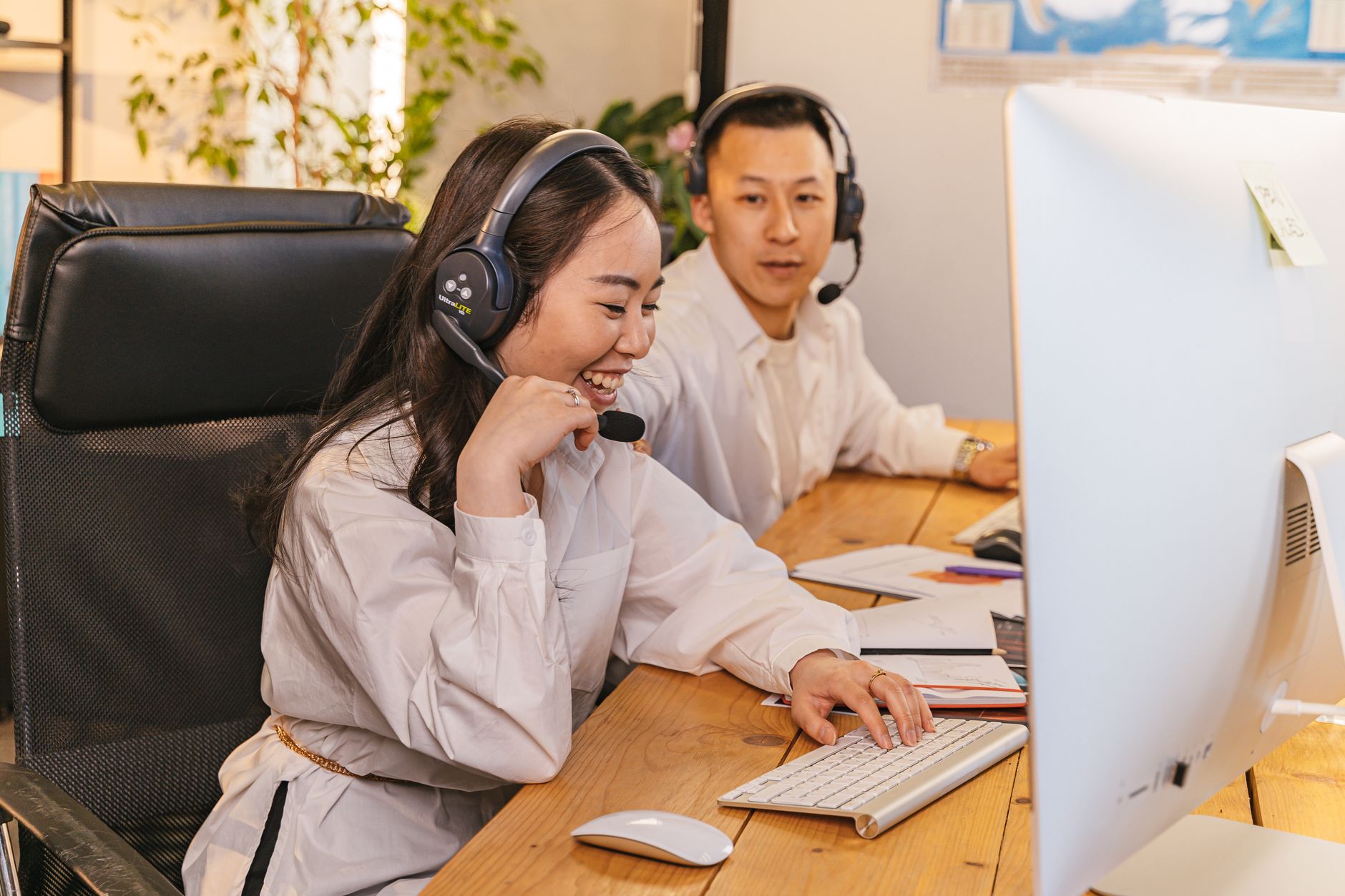 Two call center agents working together, focused and engaged at their desks, communicating via headsets.