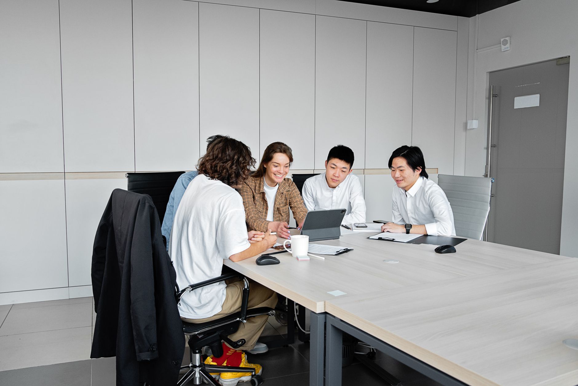 Diverse team of business professionals collaborating over a tablet in a modern office setting.