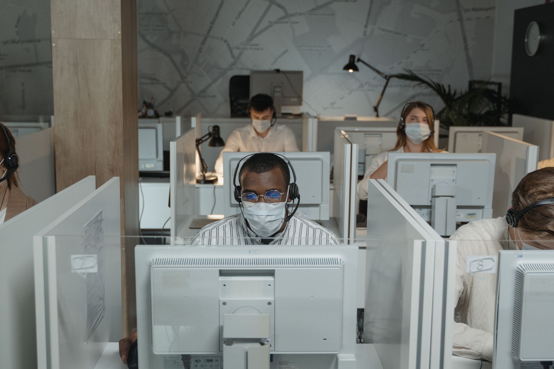 Call center agents wearing face masks working at individual stations in an office.