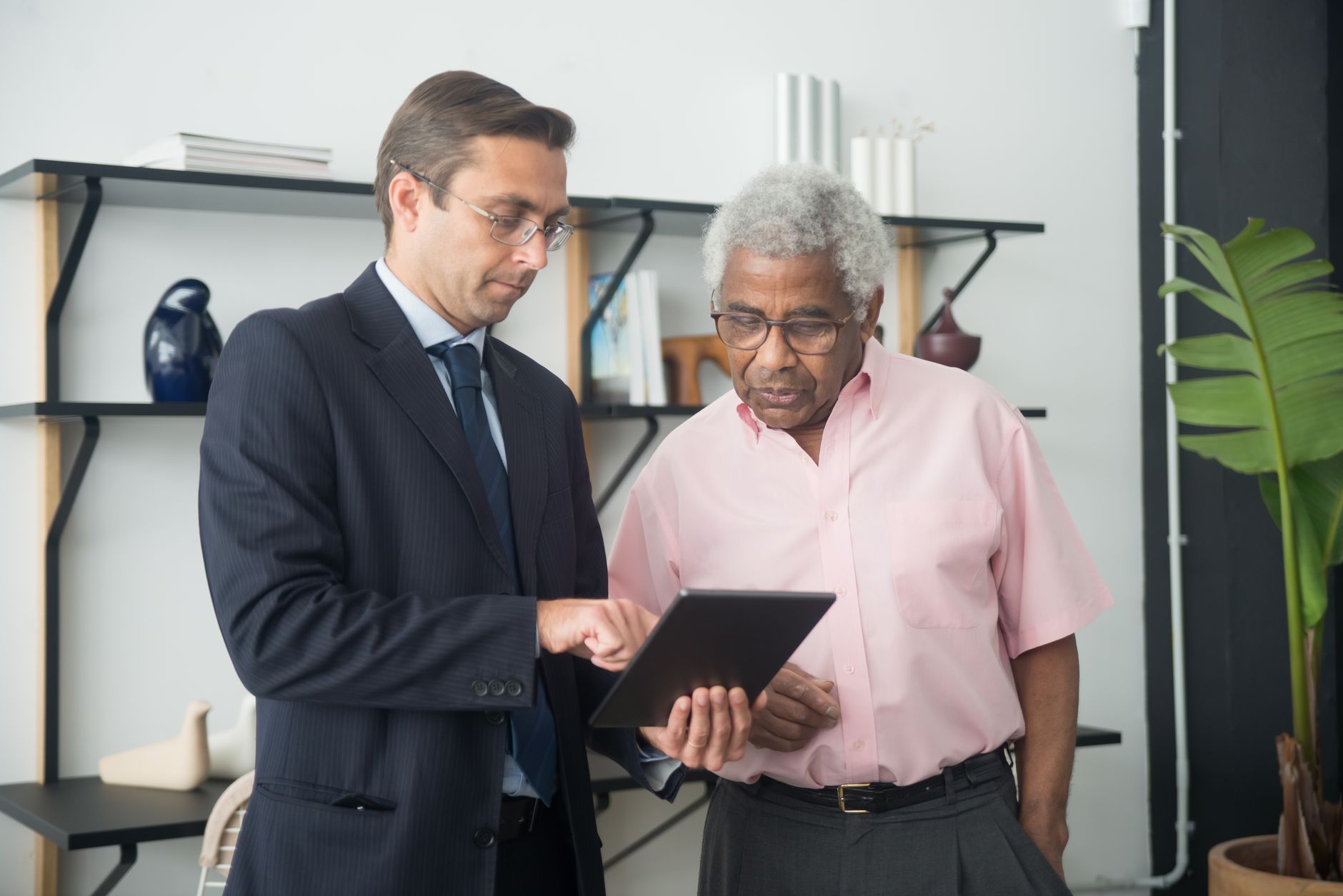 Two men discussing business strategies using a digital tablet in an office.