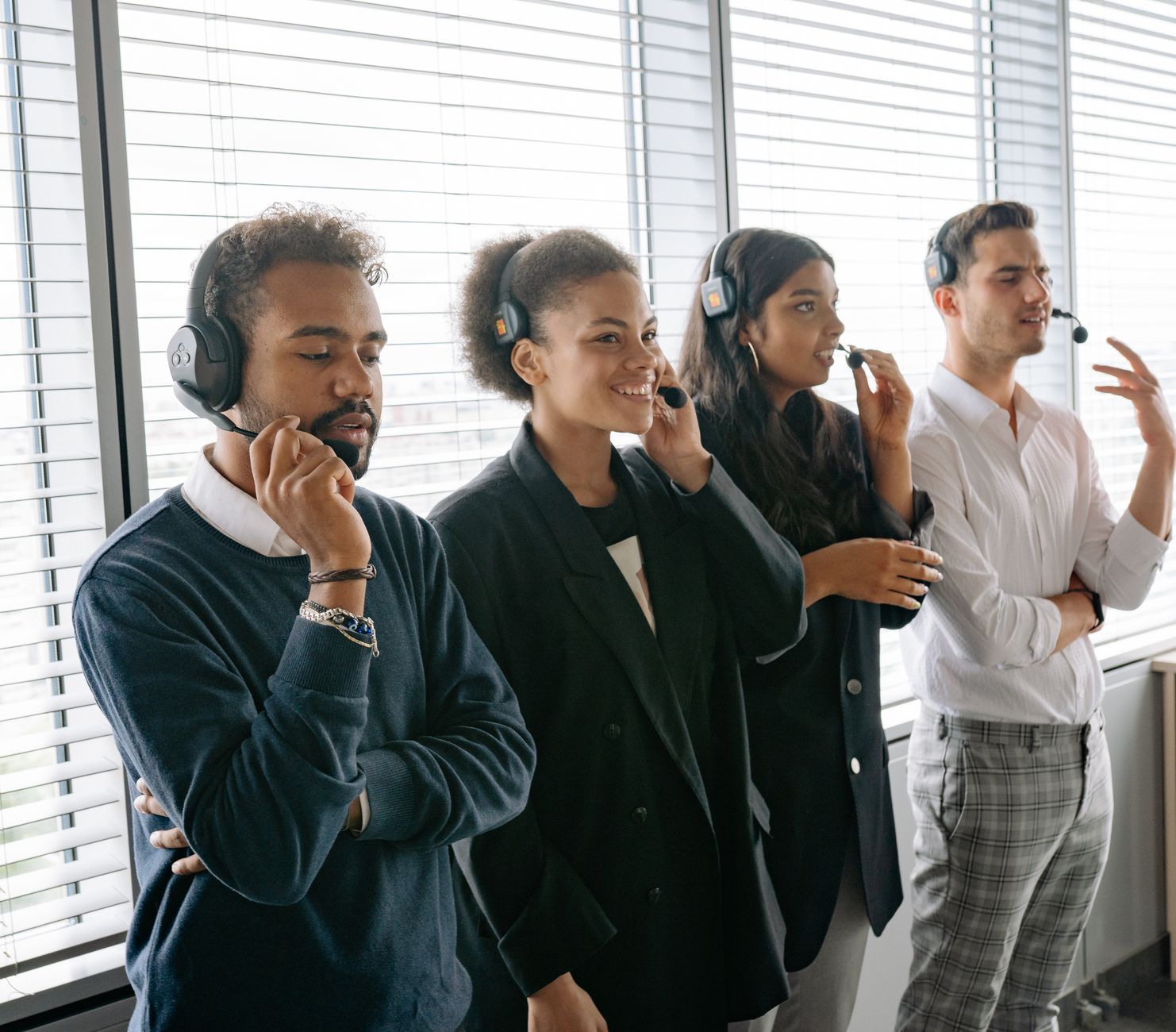 Diverse call center team collaborating in a modern office, wearing headsets and smiling.