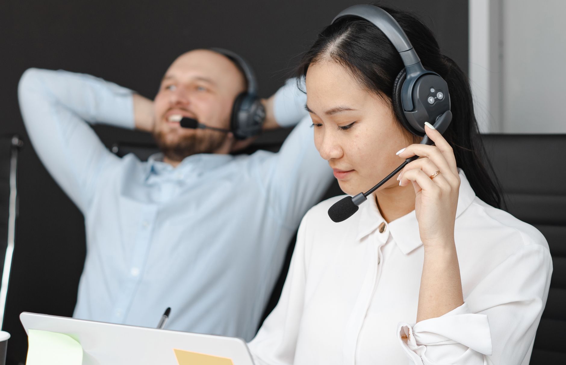 Close-up of customer service representatives with headsets working in an office.