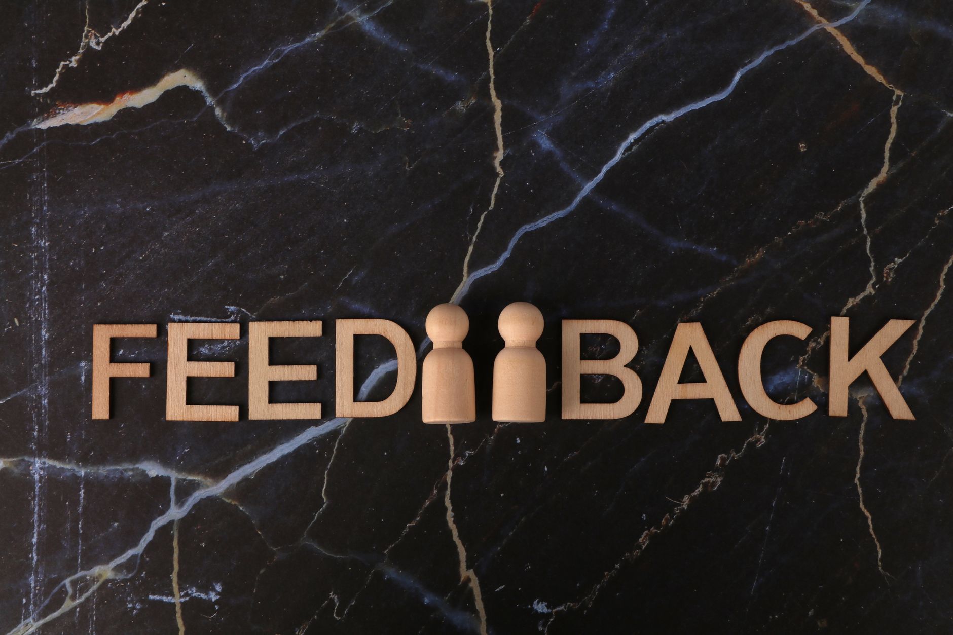 Feedback concept with wooden letters on a dark marble surface.