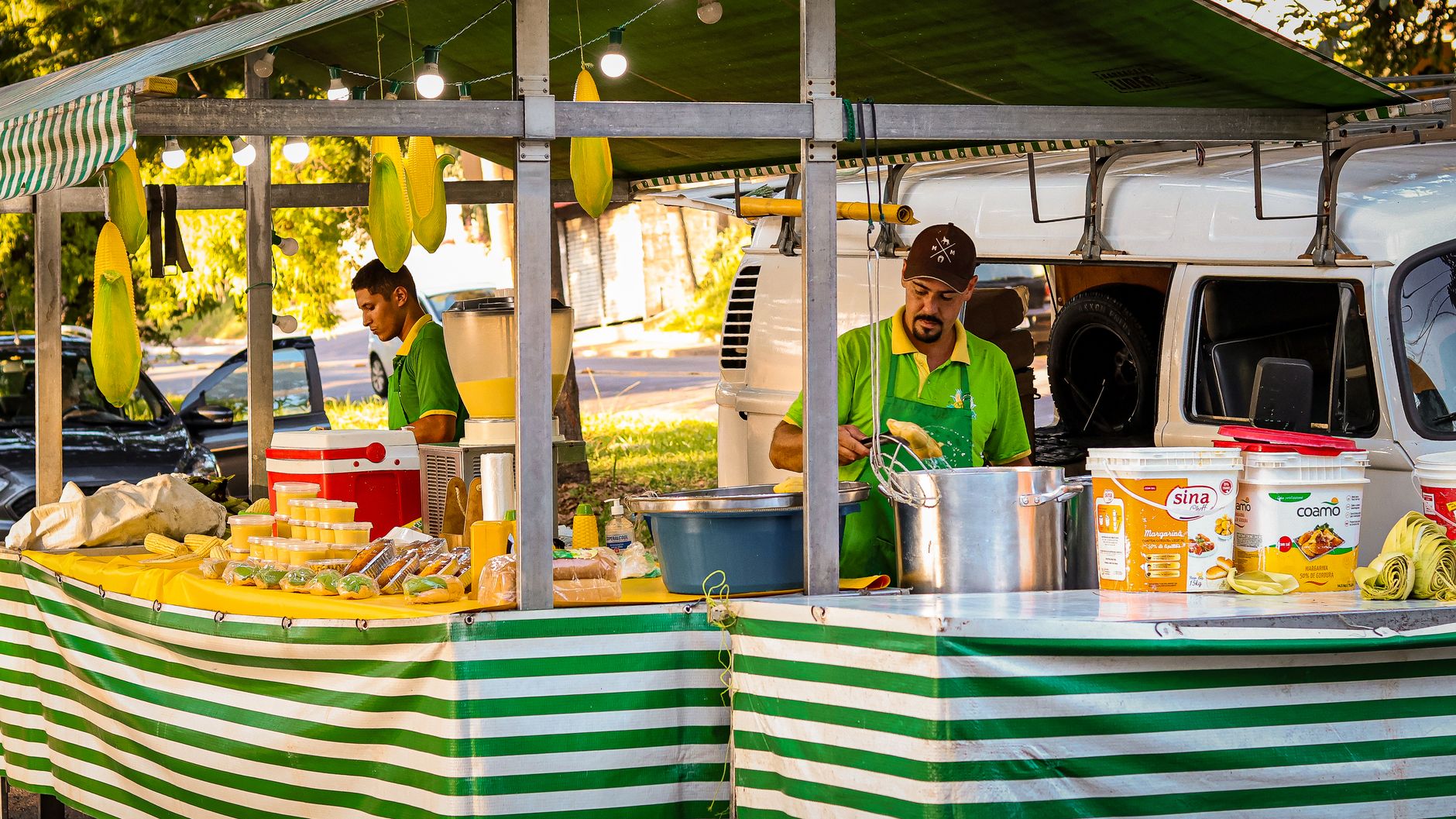 Street food stall with vendors preparing corn dishes in Campinas, Brazil.
