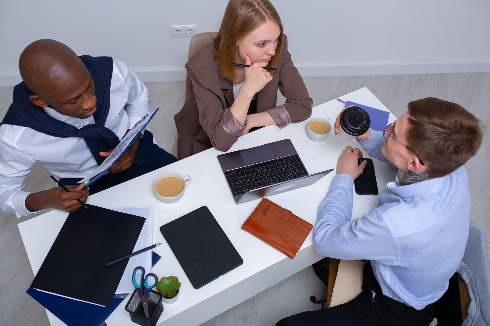 Diverse colleagues engaged in discussion around a conference table with technology and notes.