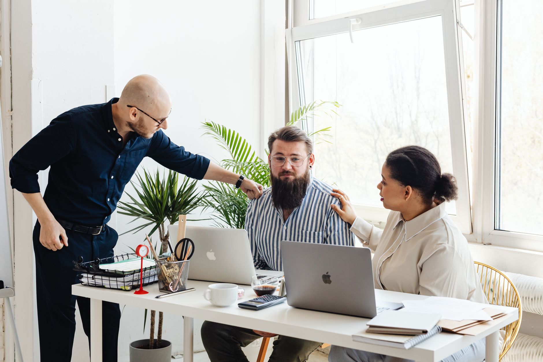 Three colleagues collaborating at a desk in a bright office space.