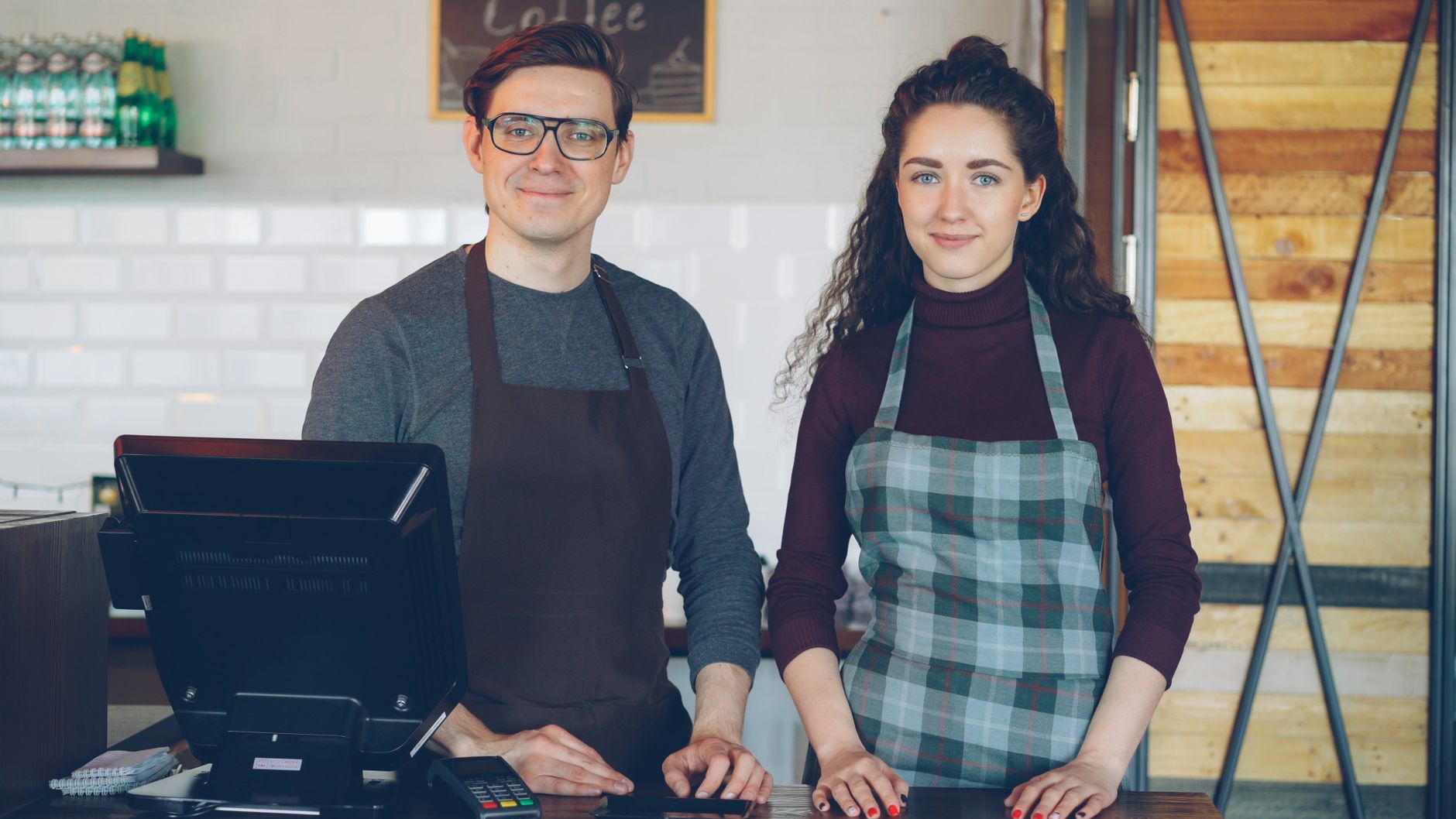 Smiling cafe employees standing behind the counter, ready to serve customers.