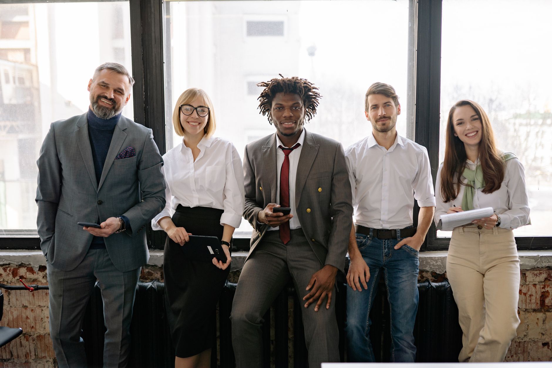 A diverse group of professionals smiling and posing together in a modern office environment.