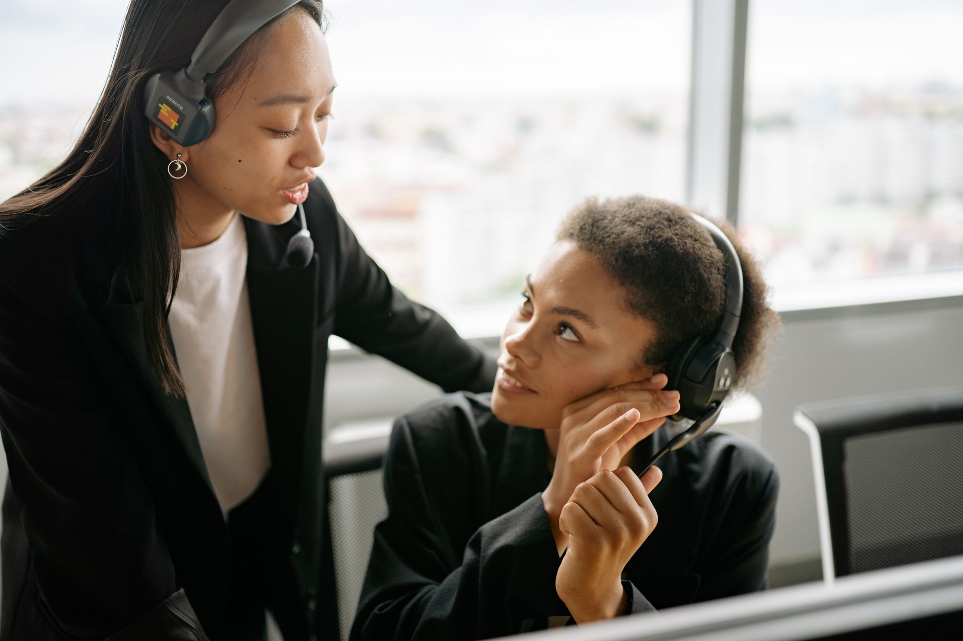 Two call center agents discussing strategies with headsets in a modern office setting.