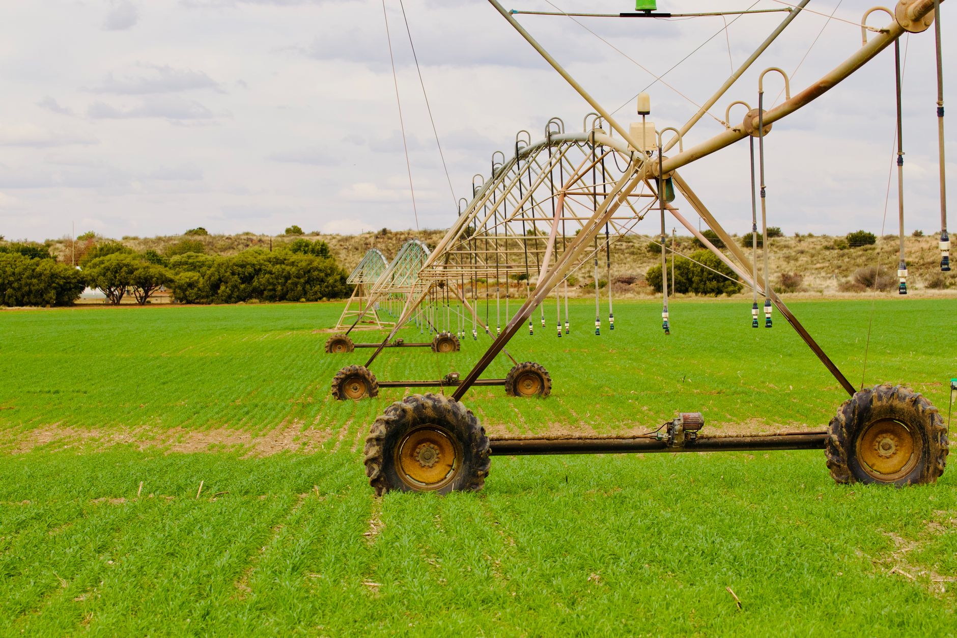 An advanced irrigation system waters a lush green field under a cloudy sky, enhancing farming efficiency.