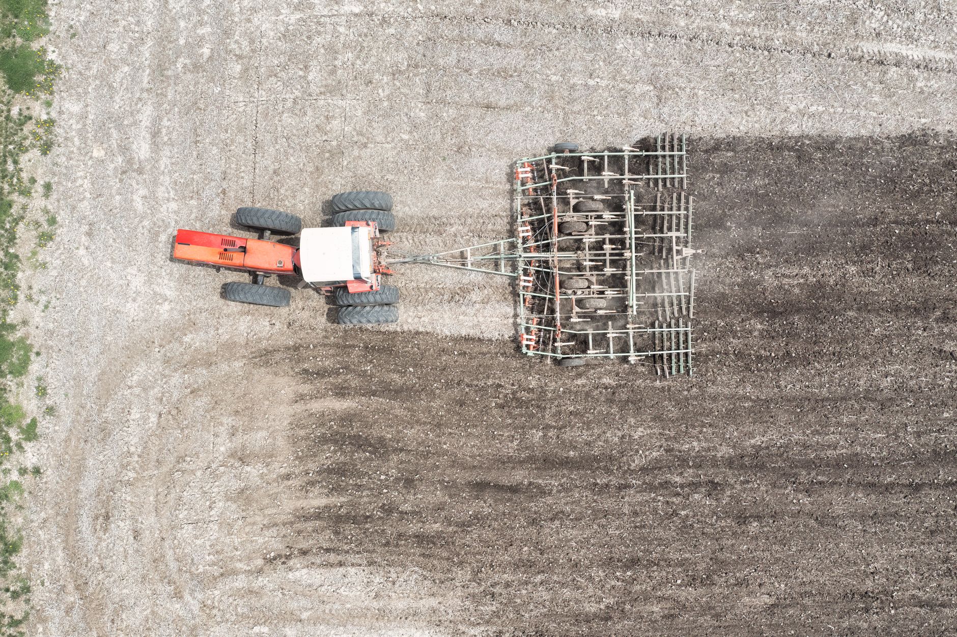 Aerial shot of a tractor tilling soil in a field, showcasing farming technology.