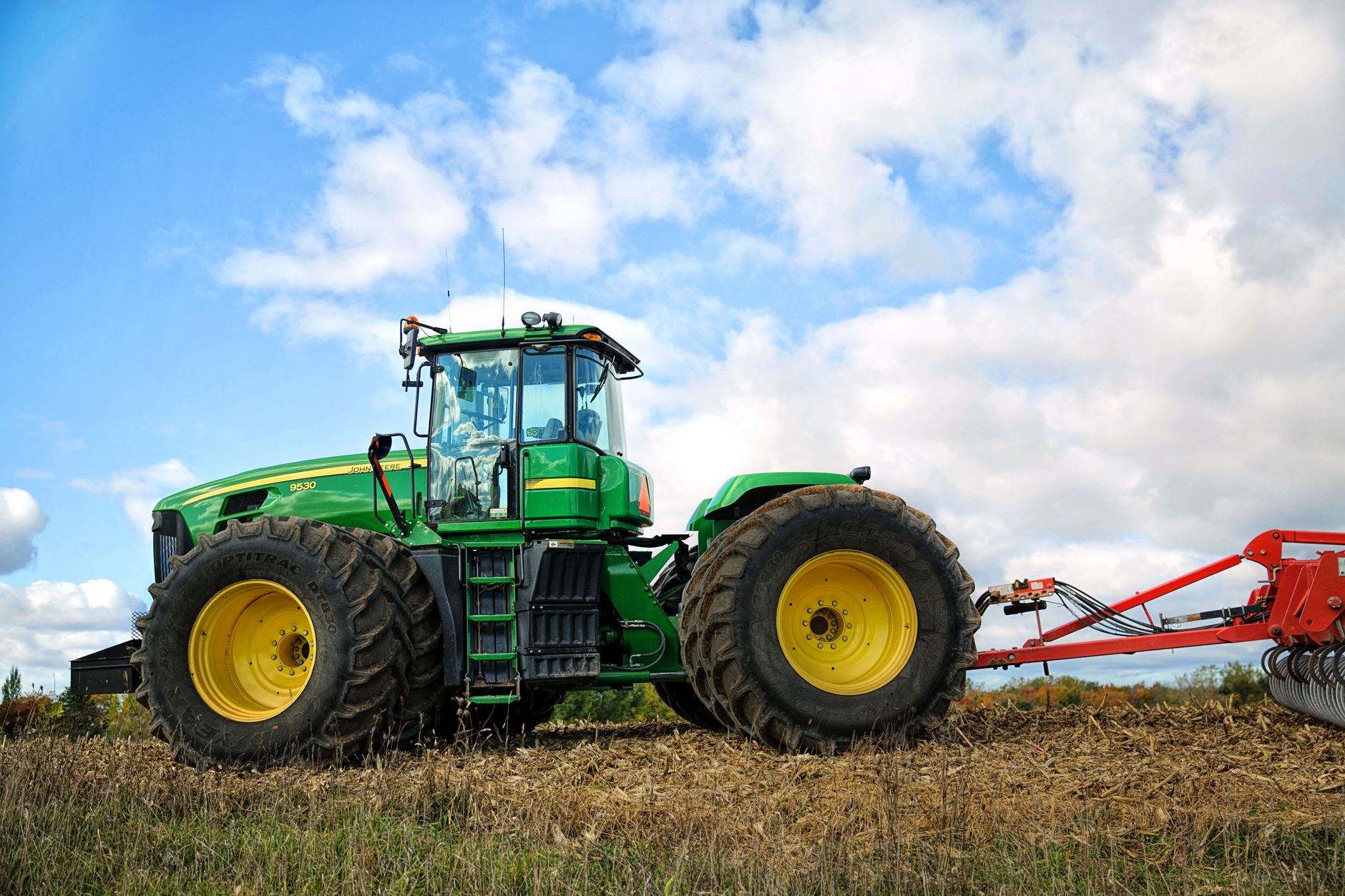 A vibrant green tractor plowing a field on a sunny day, showcasing modern agriculture.