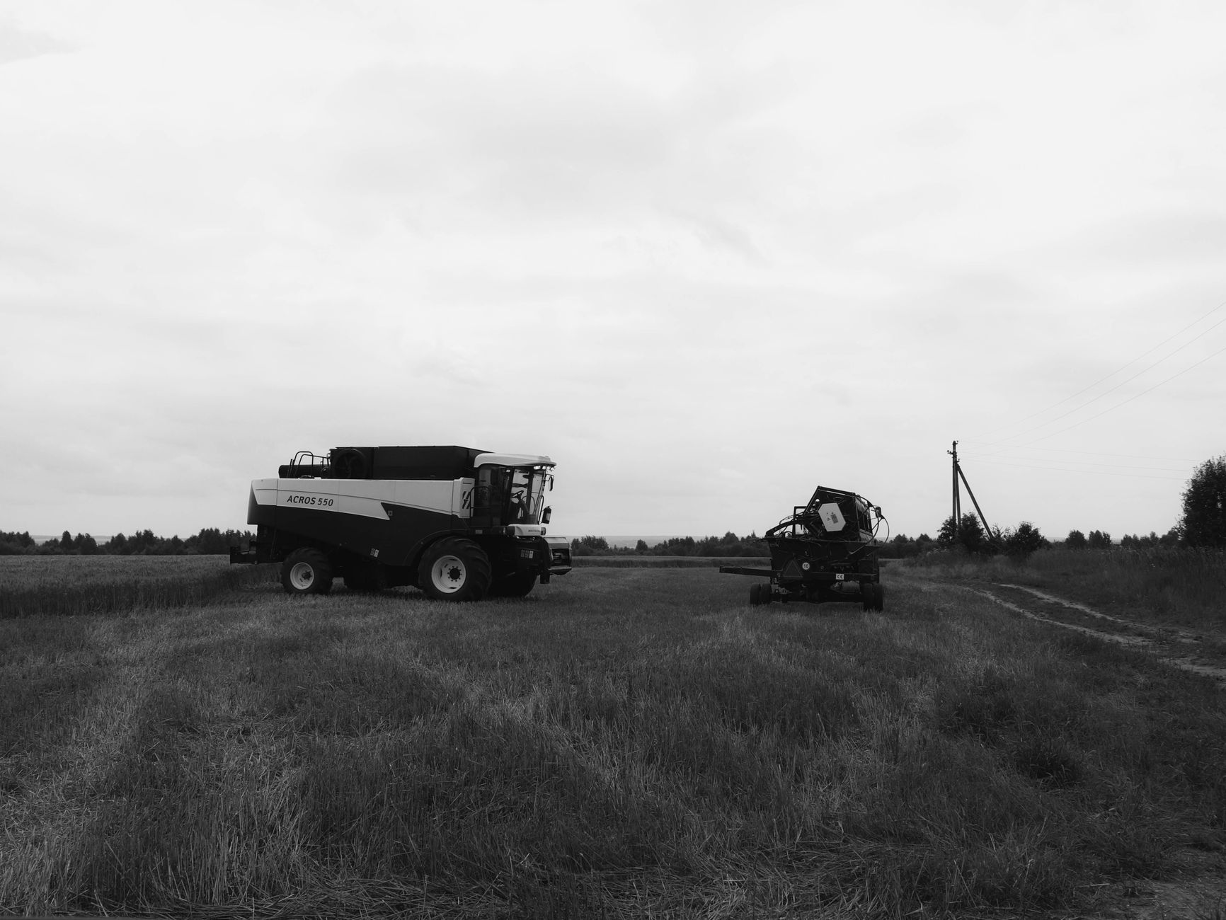 Grayscale image of combine harvester on a vast farmland, showcasing agricultural machinery.