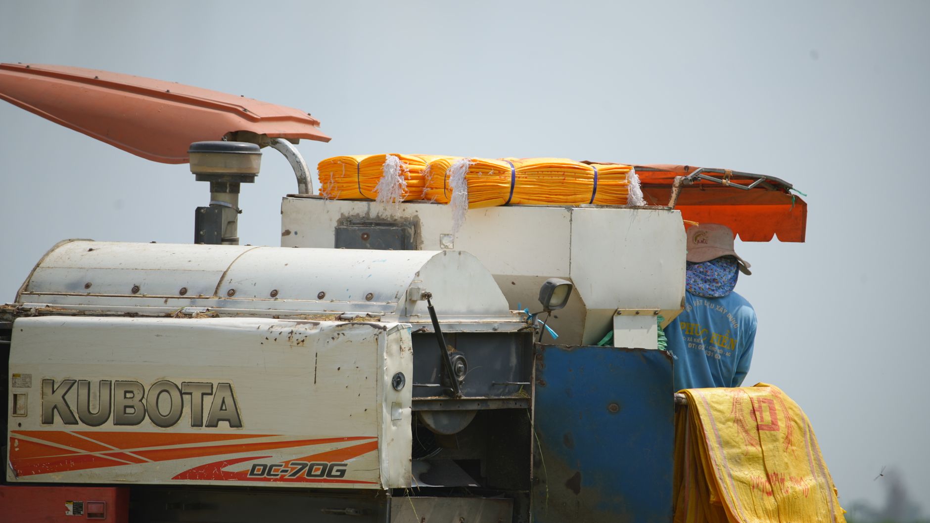 Close-up of a Kubota harvester in a field with an adult operator.