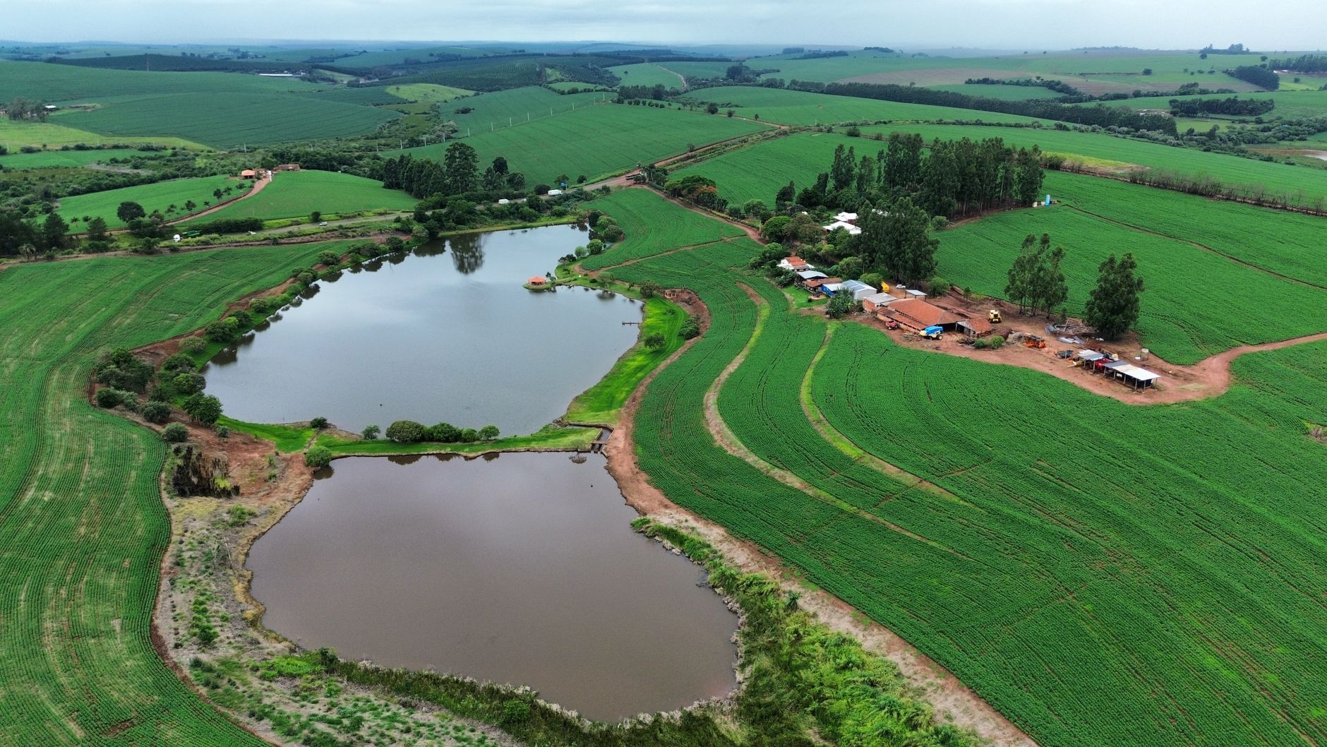 A breathtaking aerial view of a lush green farm landscape with tranquil ponds and scattered buildings.