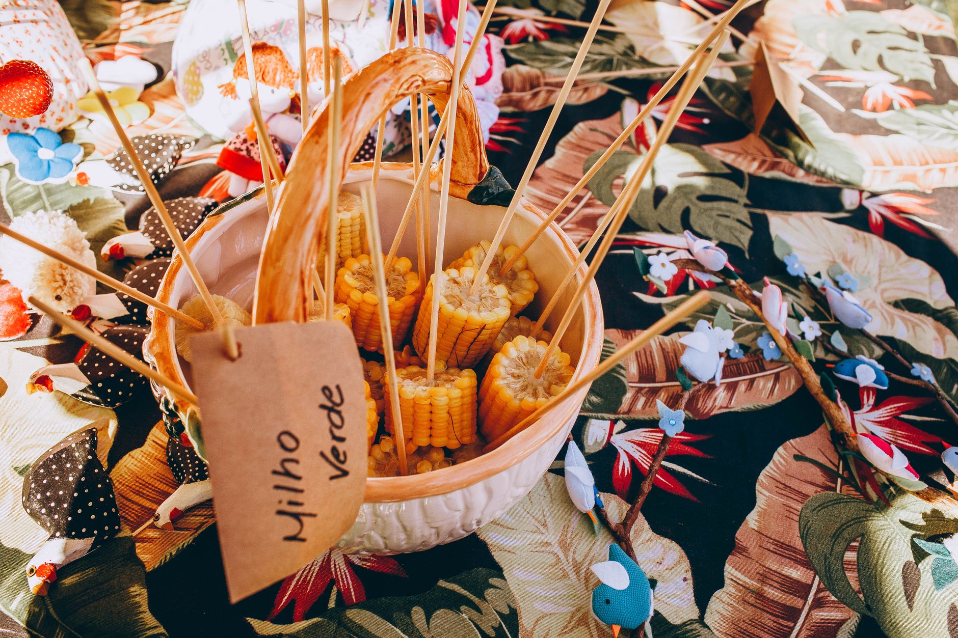 Assorted corn with wooden sticks in basket placed on tablecloth on table in market