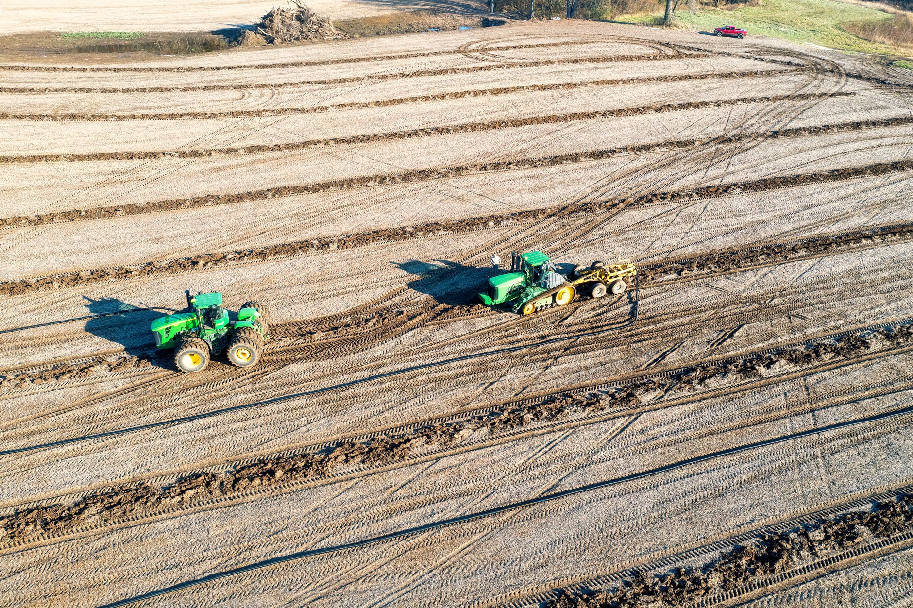 Two green tractors working in dry farmland in Kellogg, Minnesota.