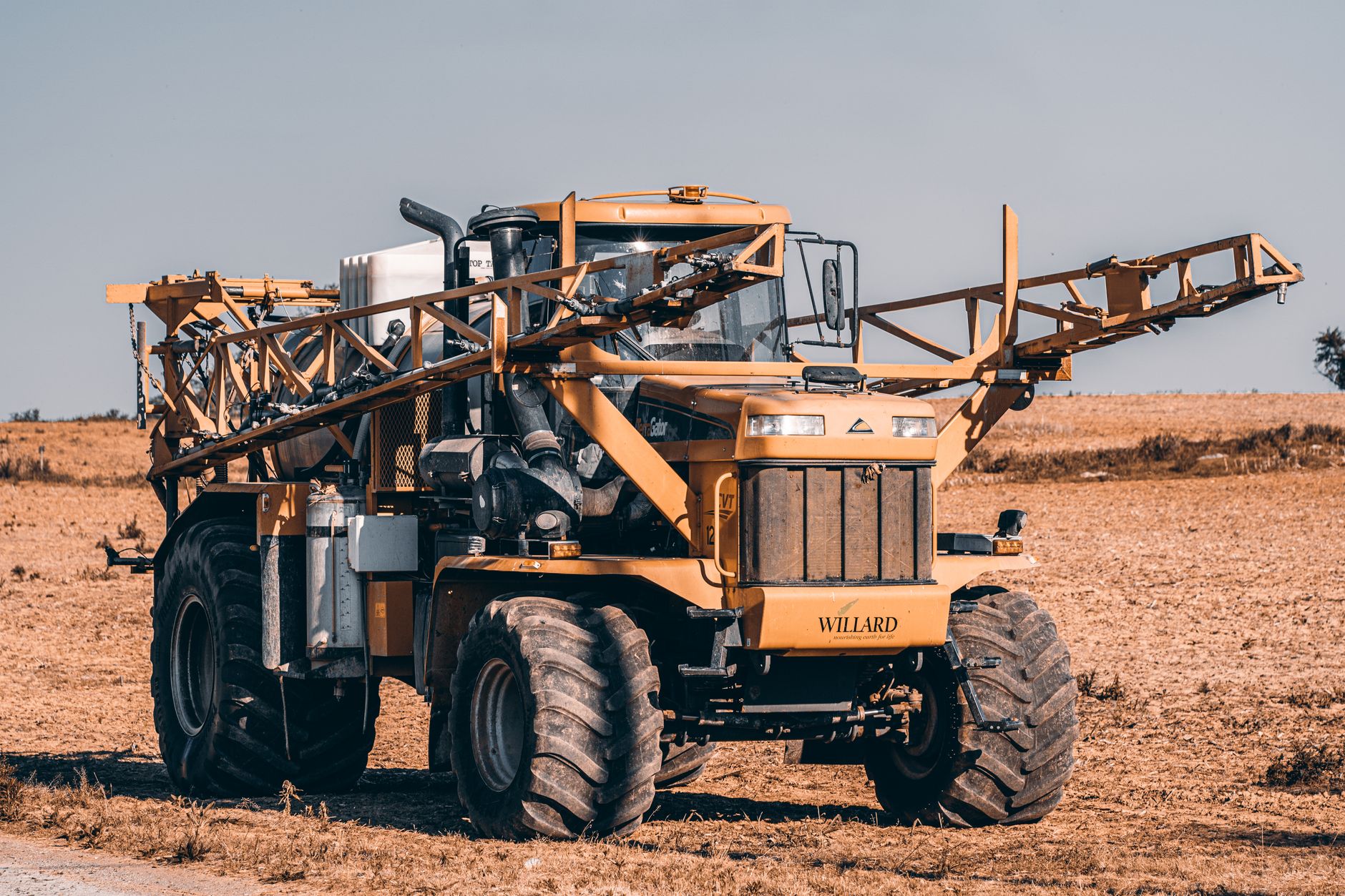 A self-propelled agricultural sprayer in a vast field showcasing modern farming technology.
