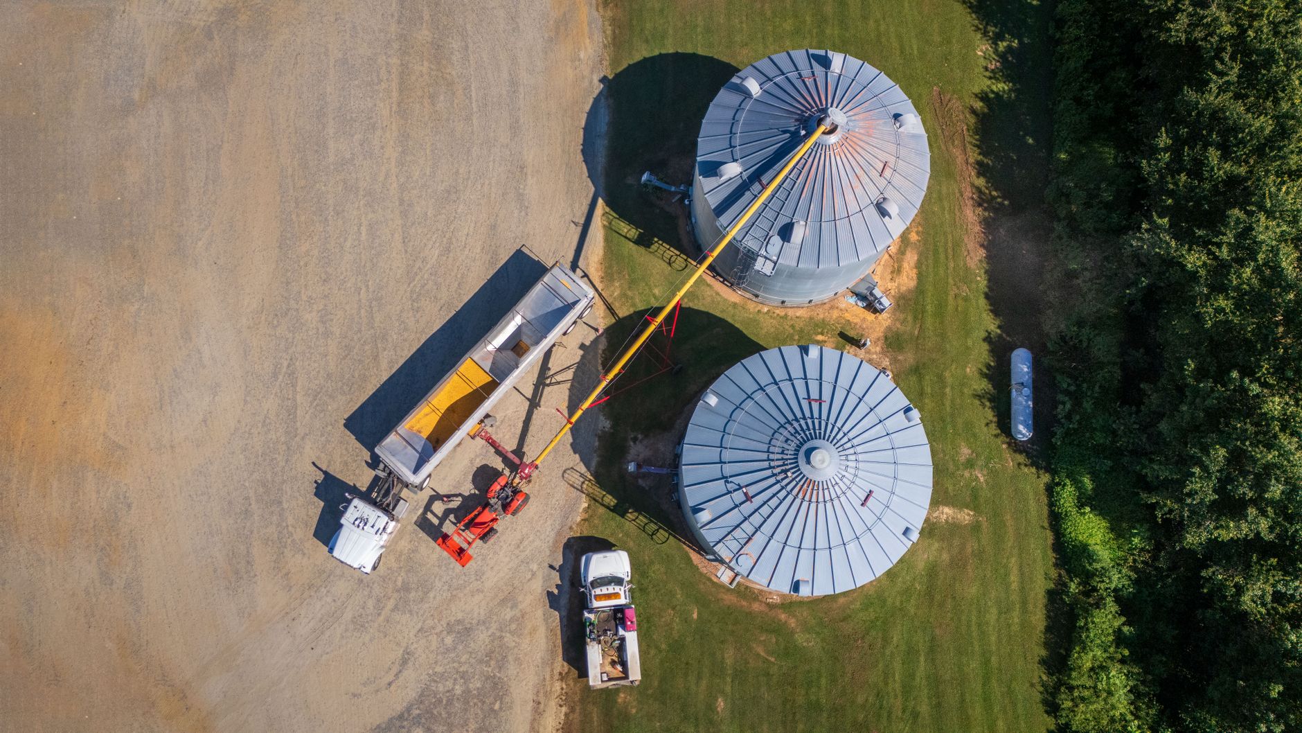Overhead shot of silos and machinery in a rural setting, highlighting farming operations.