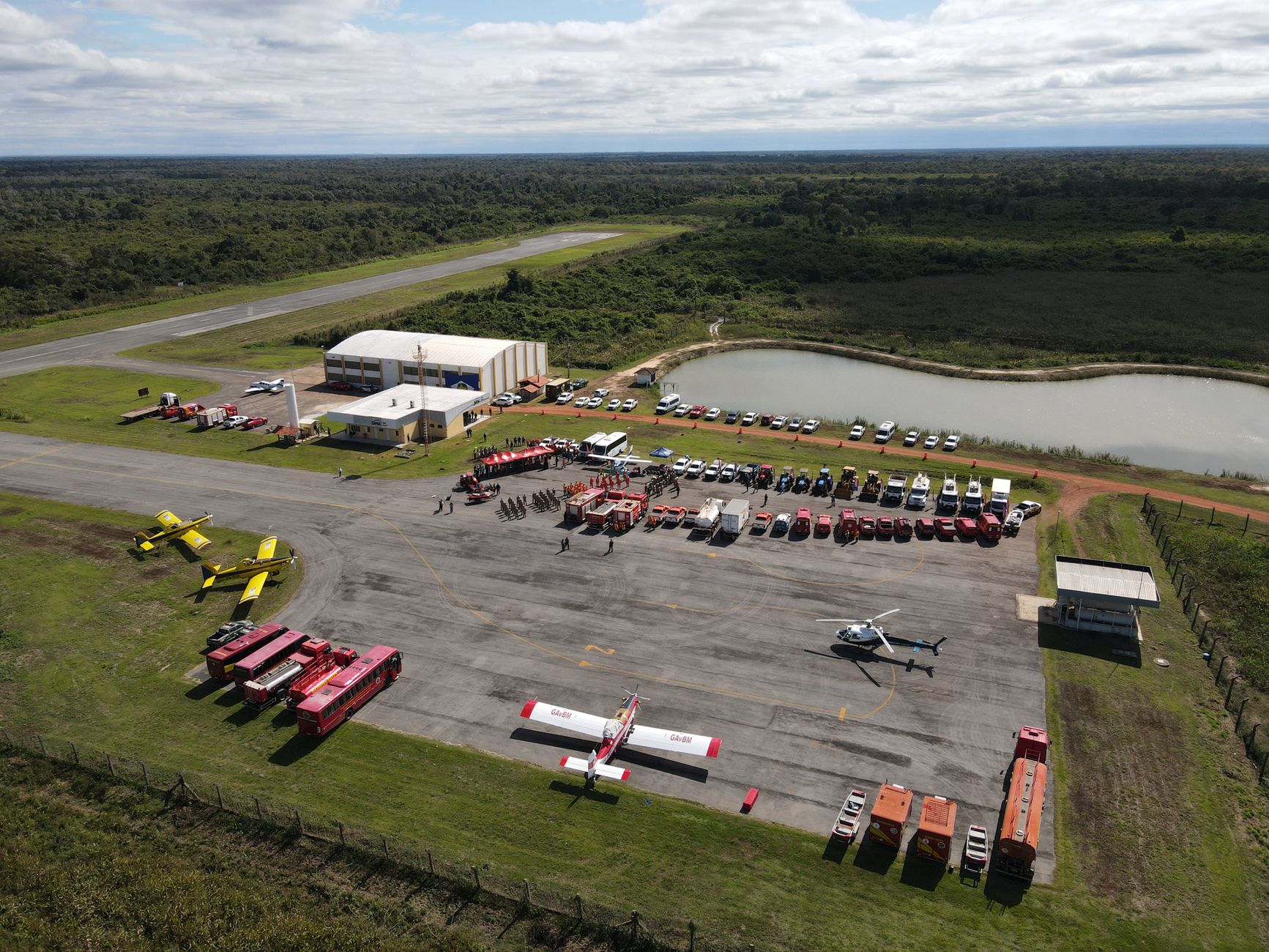 Aerial view of firefighting base in Mato Grosso, Brazil showcasing fire trucks, helicopters, and planes ready for action.