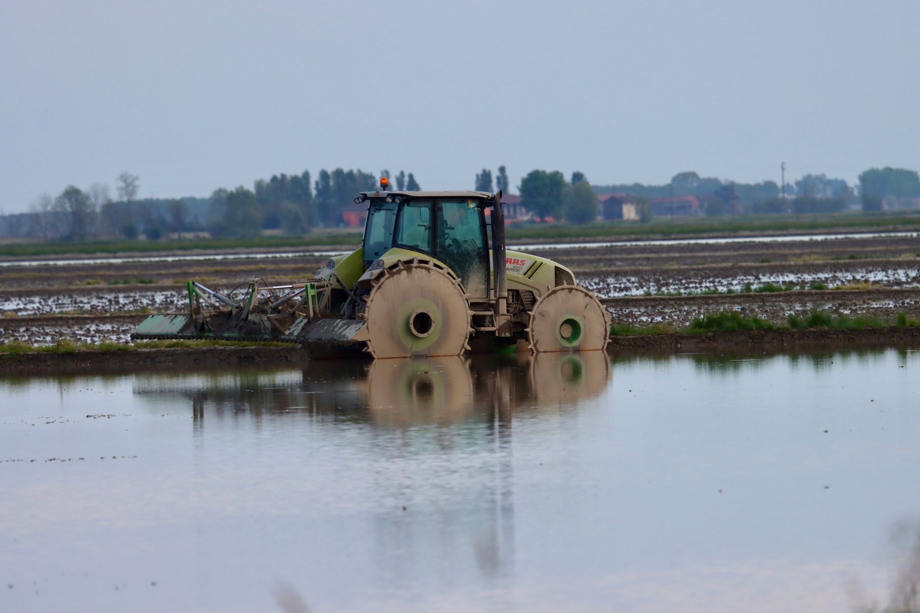 A tractor reflected in a flooded paddy field in Novara, Italy.