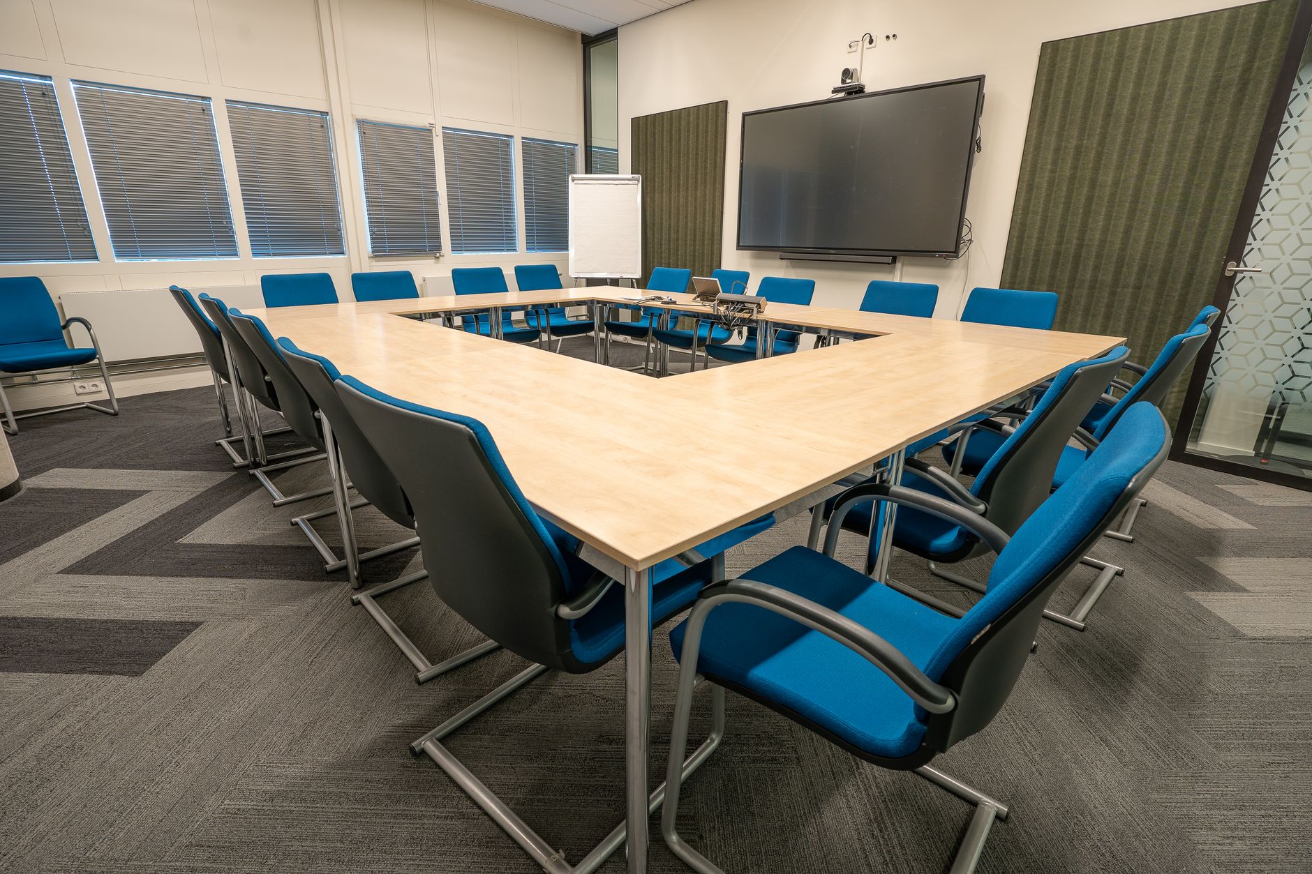 A modern conference room with a U-shaped table and blue chairs, perfect for meetings.