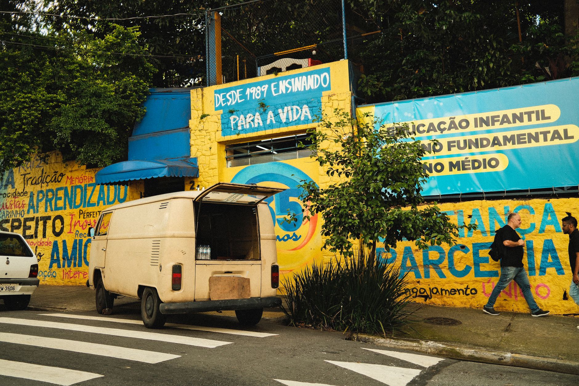 Vibrant street scene featuring a vintage van against a colorful school mural promoting education.
