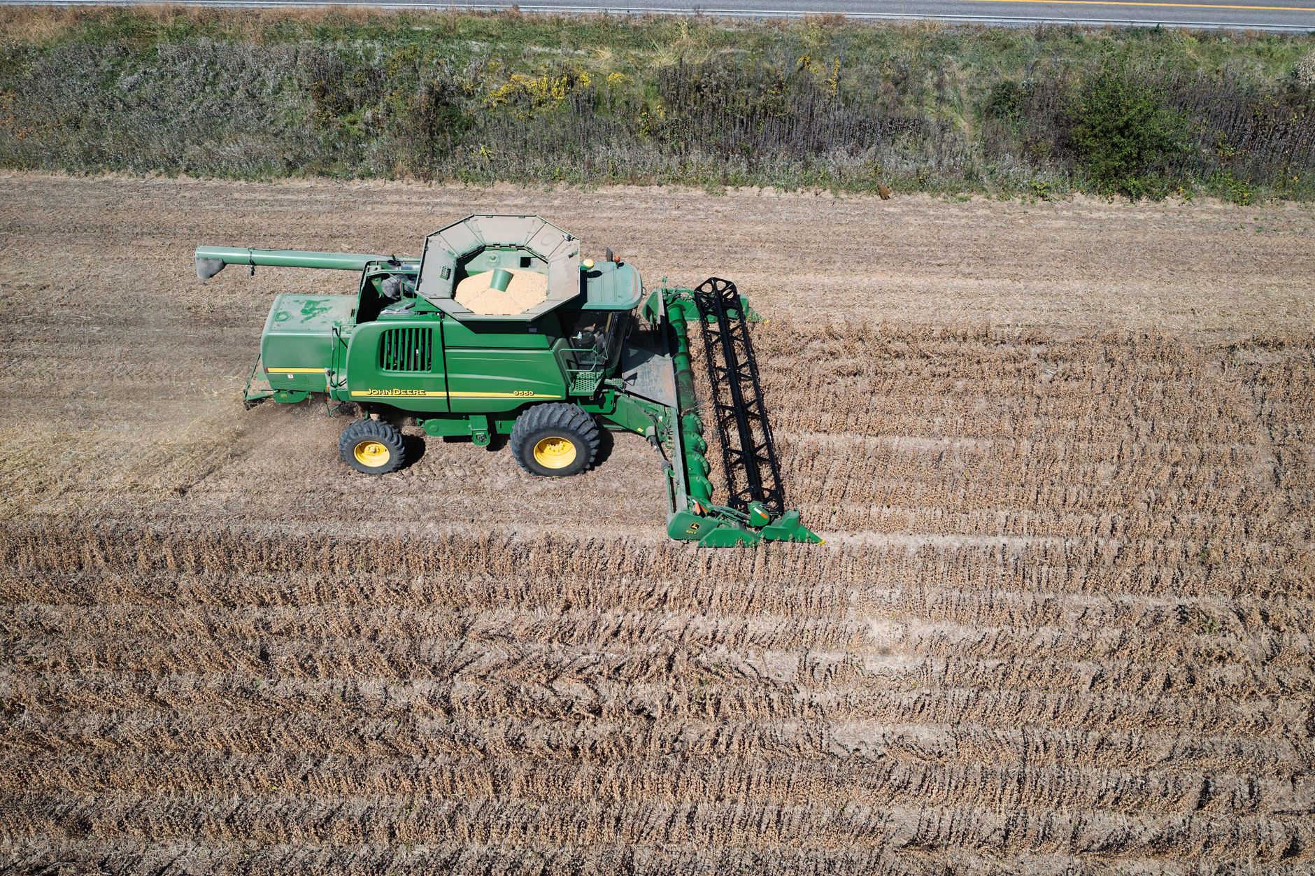 Aerial shot capturing a green combine harvester working in a West Albany field during harvest season.