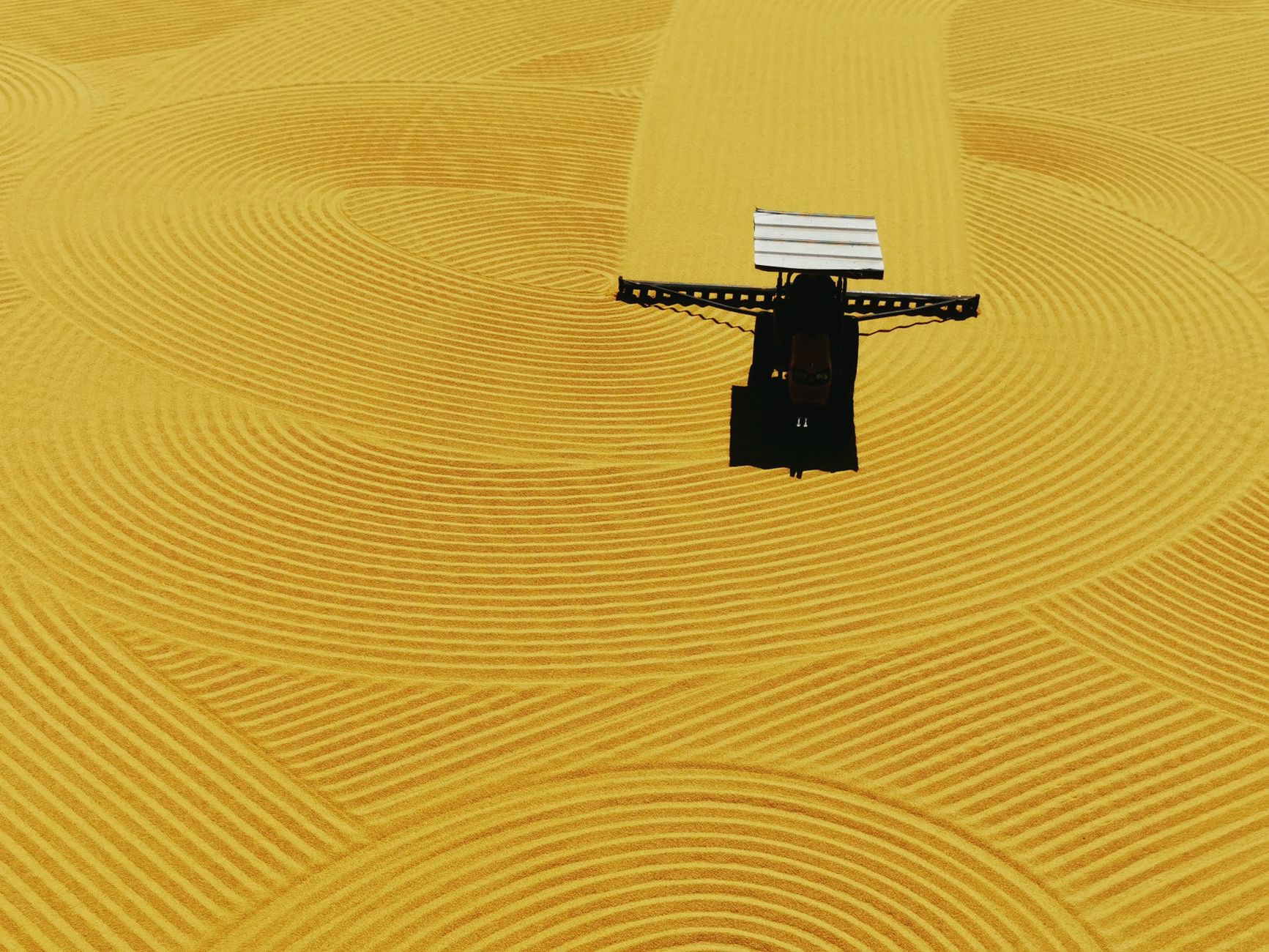 A drone captures a tractor making intricate patterns in the sand, showcasing precision maintenance.