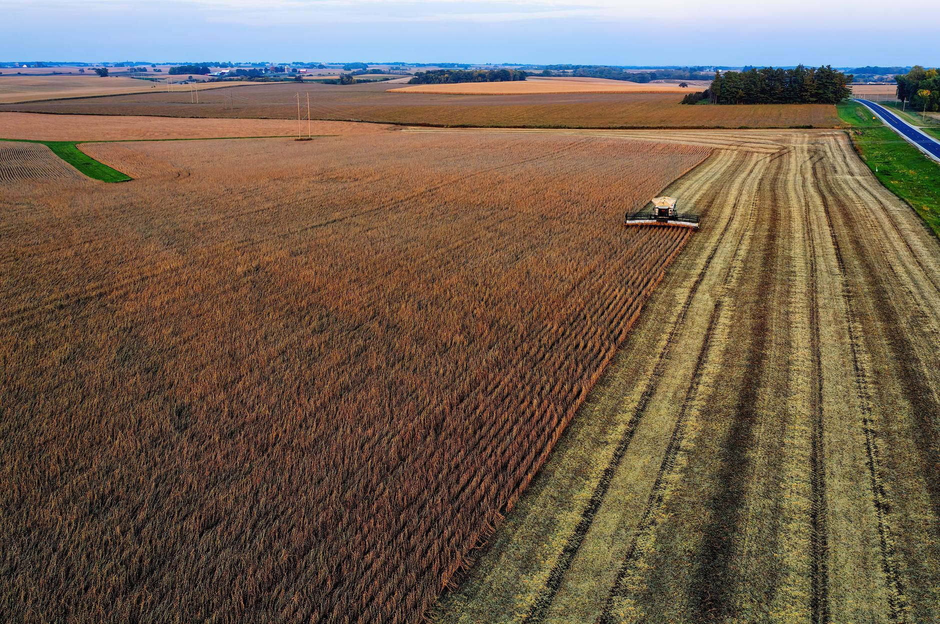Aerial view of a combine harvester working in expansive cropland in Minnesota, USA.