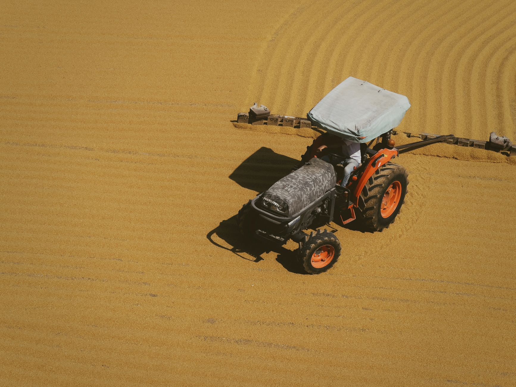 A tractor working on a golden field, viewed from above, showing modern agricultural techniques.