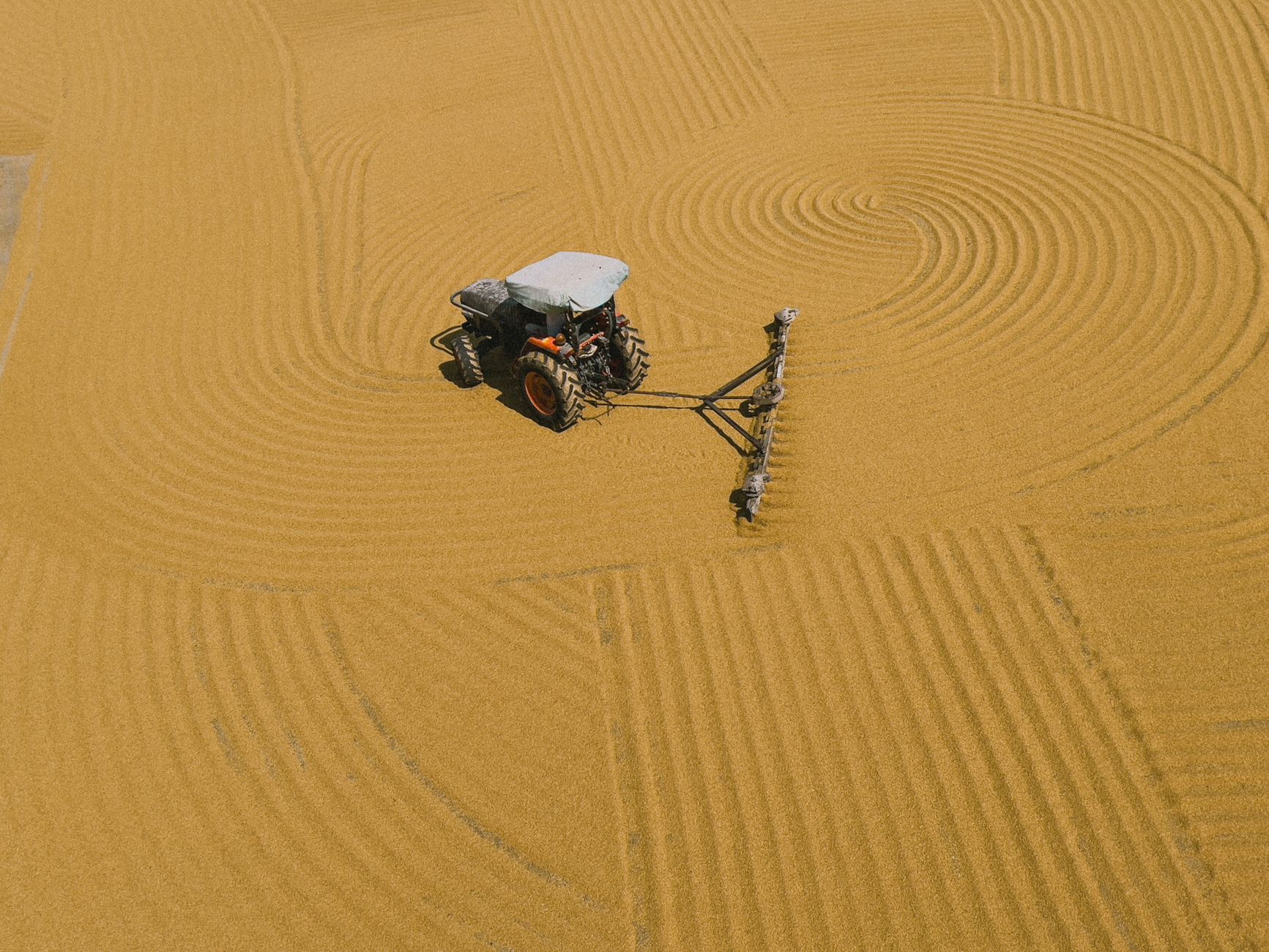 An aerial view of a tractor creating intricate patterns in a golden wheat field, showcasing agricultural technology.