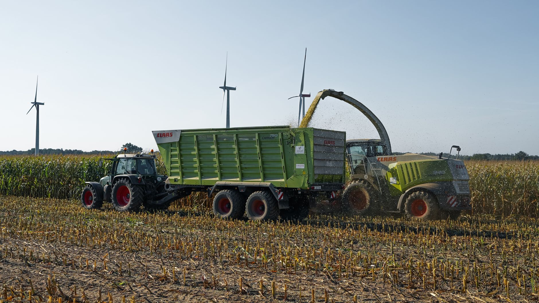 Harvesting corn with tractors and wind turbines in Lütau, Germany.