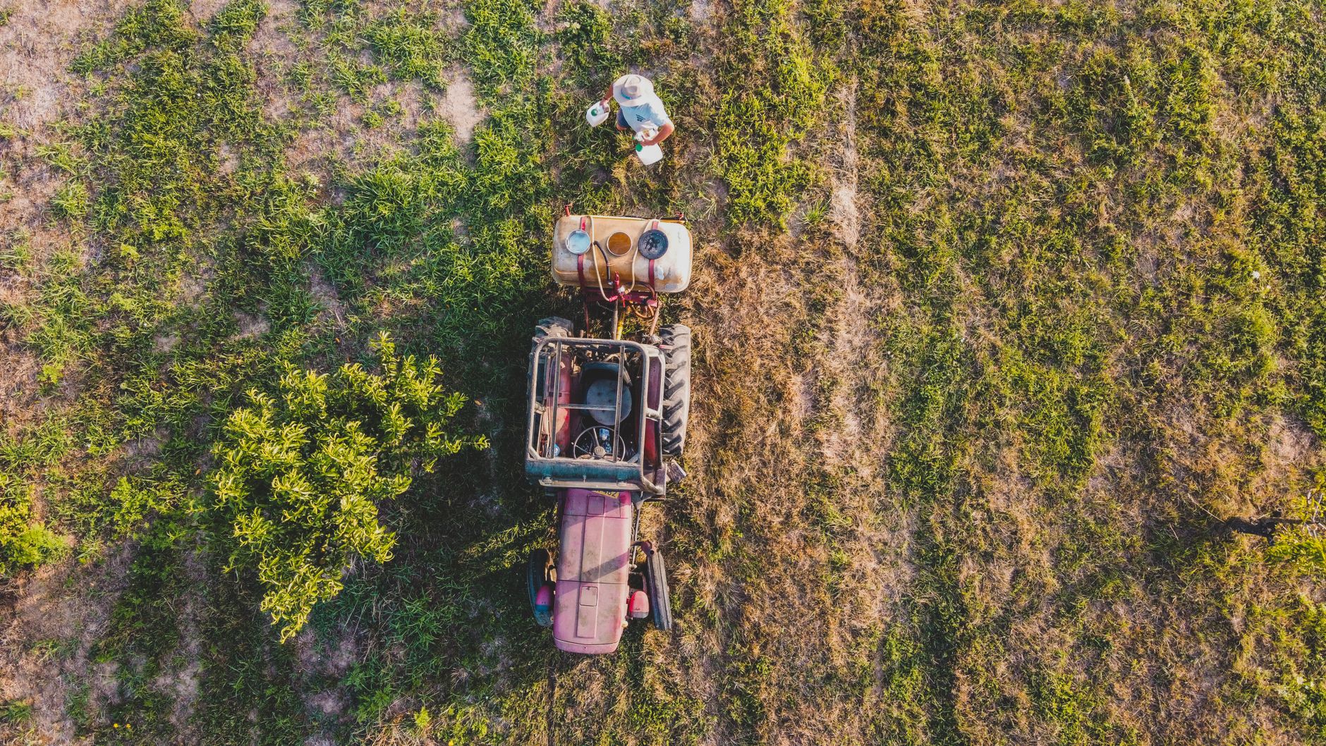 Aerial shot of a farmer with a tractor working in a field in Budapest, showcasing agriculture.