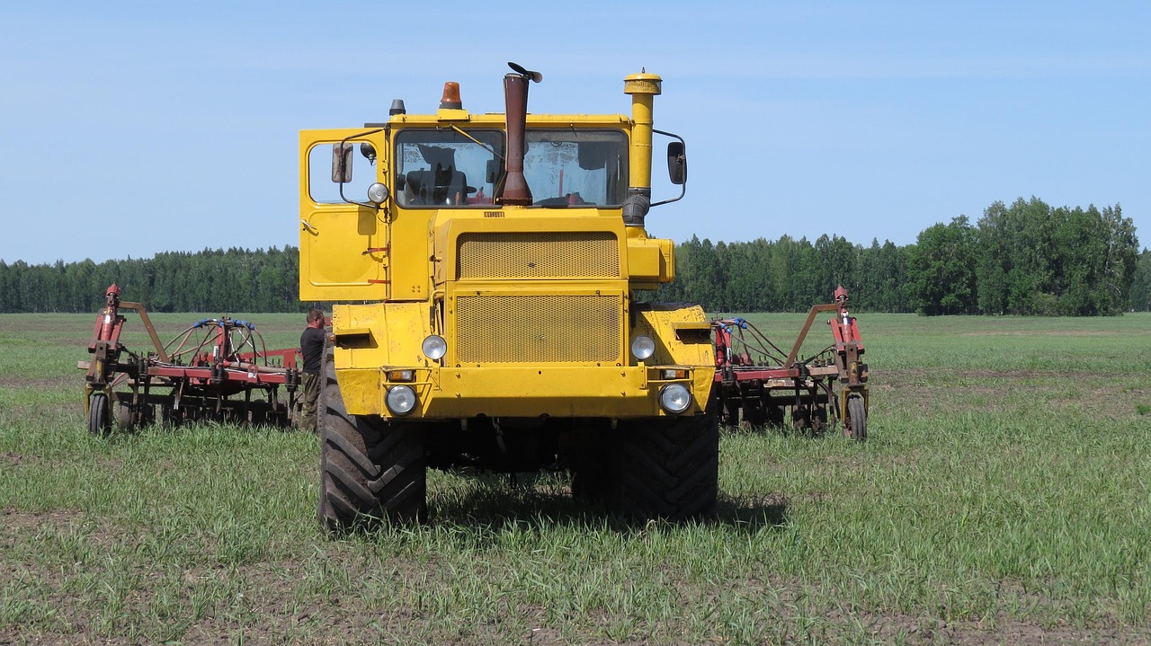 Fazendeiro arando campo com trator moderno