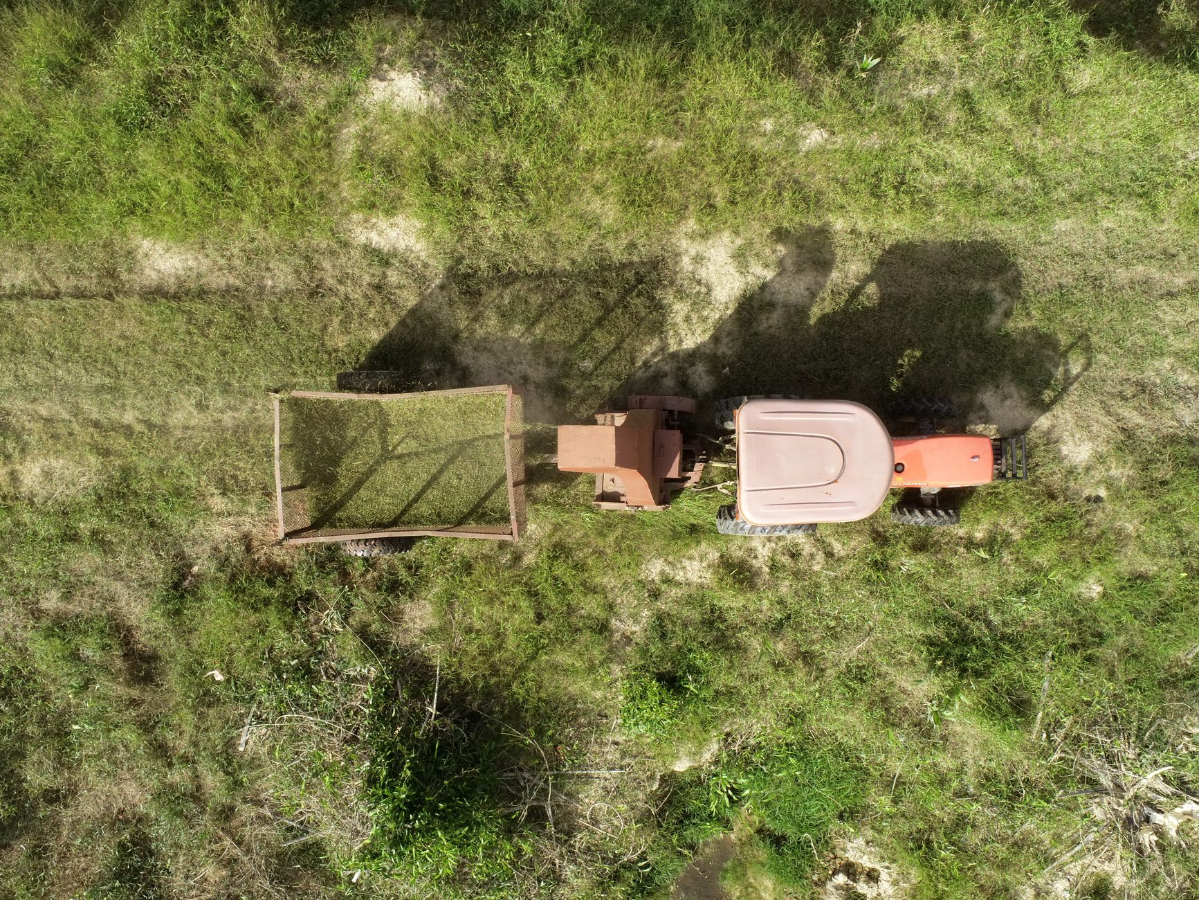 Aerial view of a tractor mowing a grassy field in Terengganu, Malaysia.