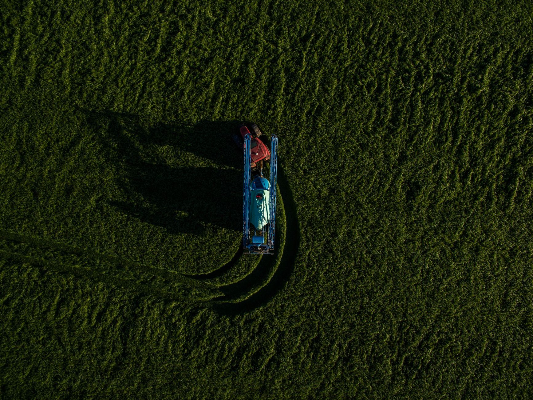 Aerial view of a tractor mowing a lush green field near Bucharest, Romania.
