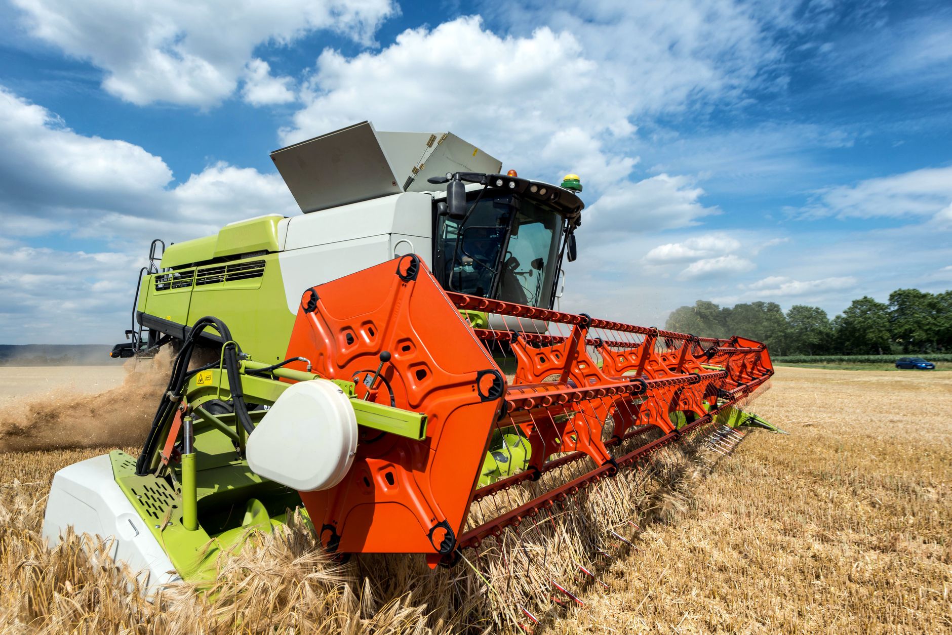 A bright image of a combine harvester working in a golden wheat field under a clear blue sky.