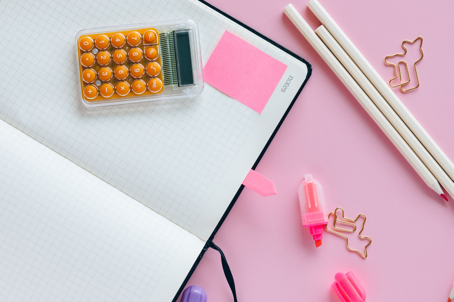 Aesthetic flat lay of colorful stationery items on a pink background, perfect for creative workspace inspiration.