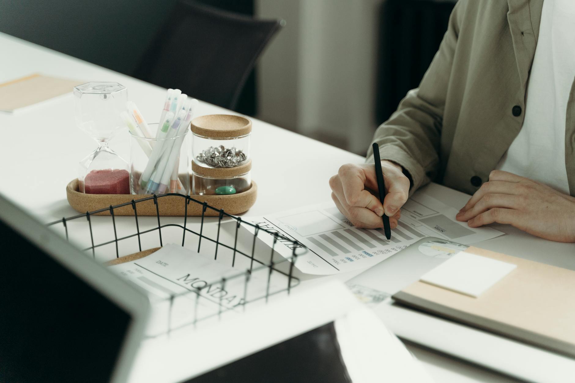 A person writing on a document at a tidy desk with office supplies.